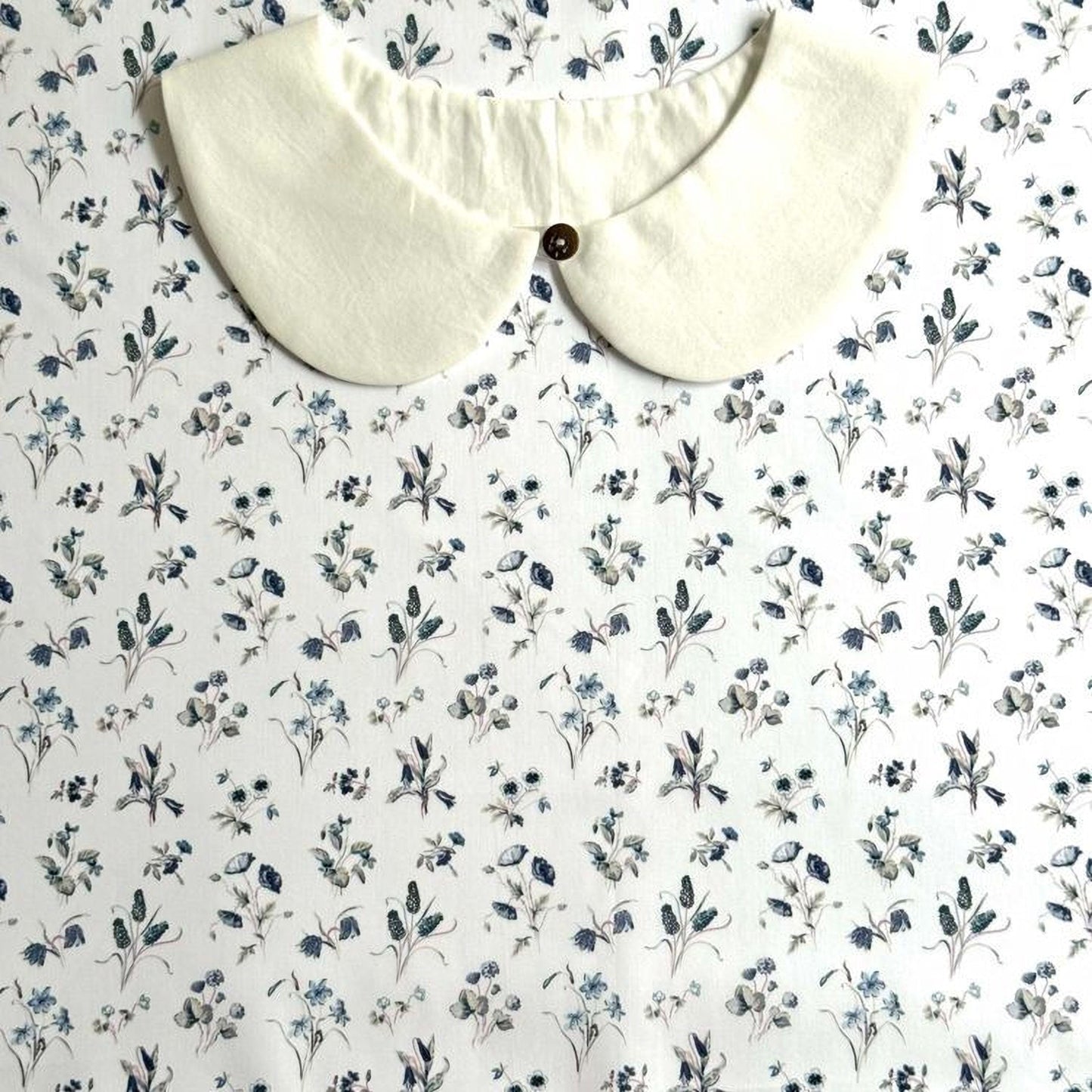 a white collar with a button, set against a background with a floral print.