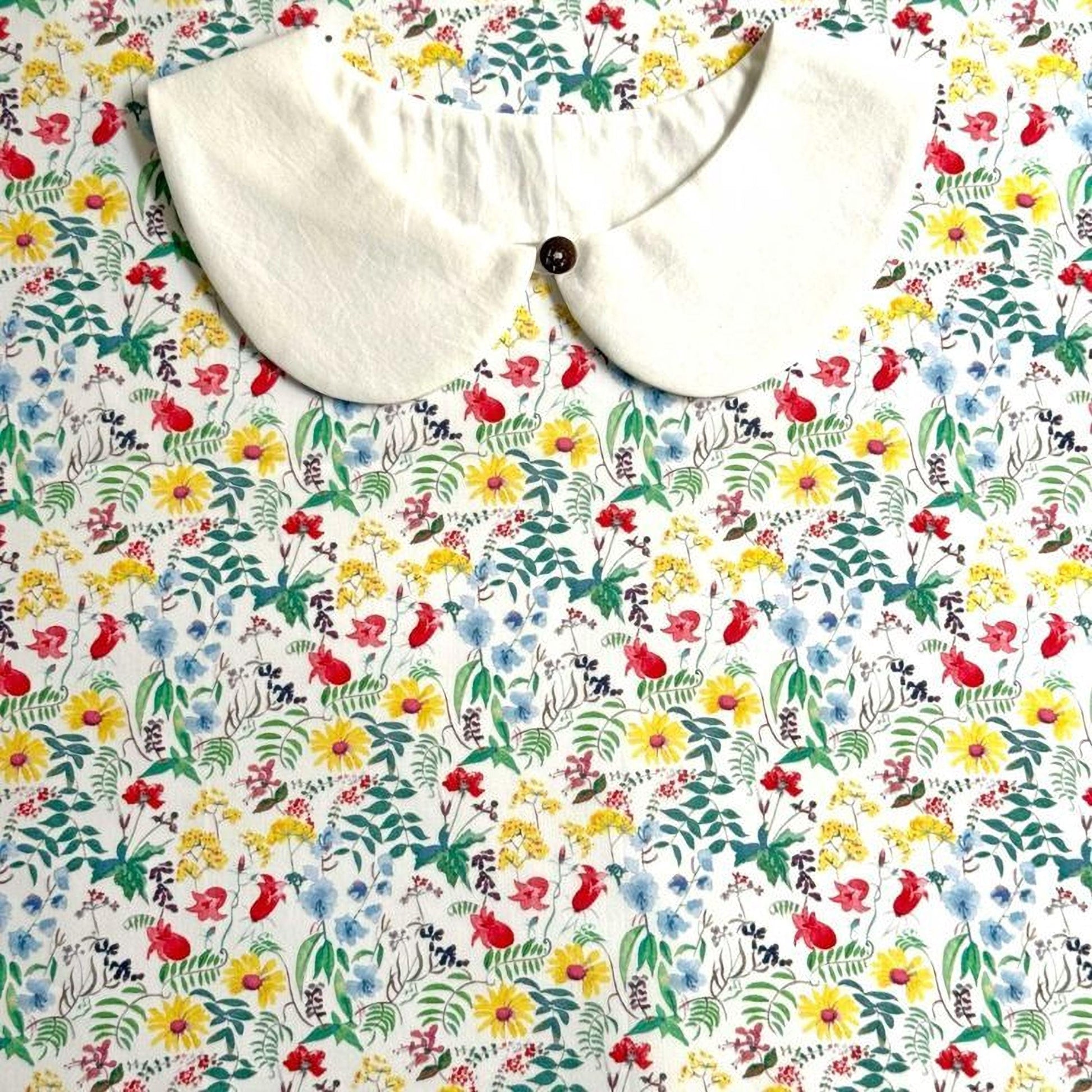 a white collar with a button, set against a background of a colorful floral print.