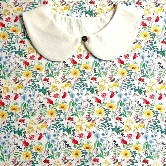 a white collar with a button, set against a background of a colorful floral print.