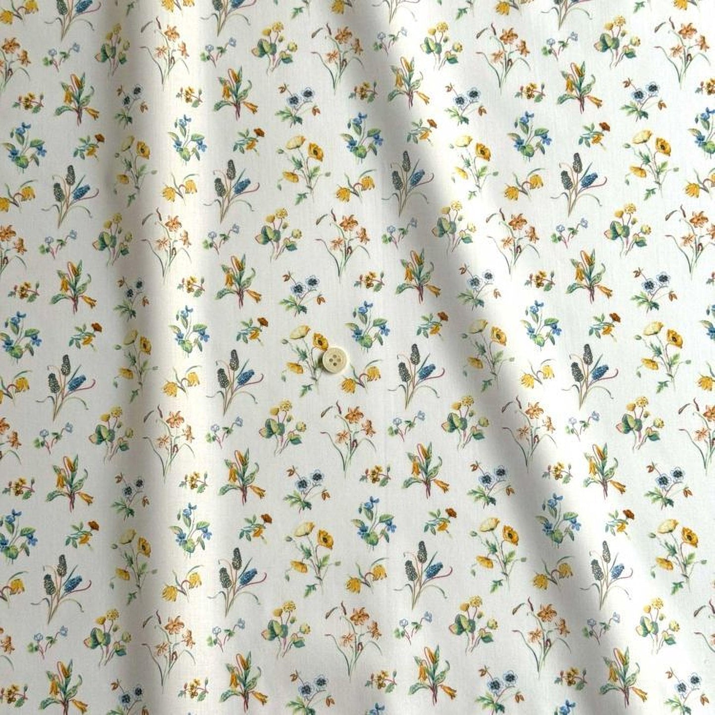 a close-up view of a fabric with a repeating floral pattern in various colors, including yellow, orange, and green. The pattern consists of small flowers and leaves, creating a visually appealing and intricate design.
