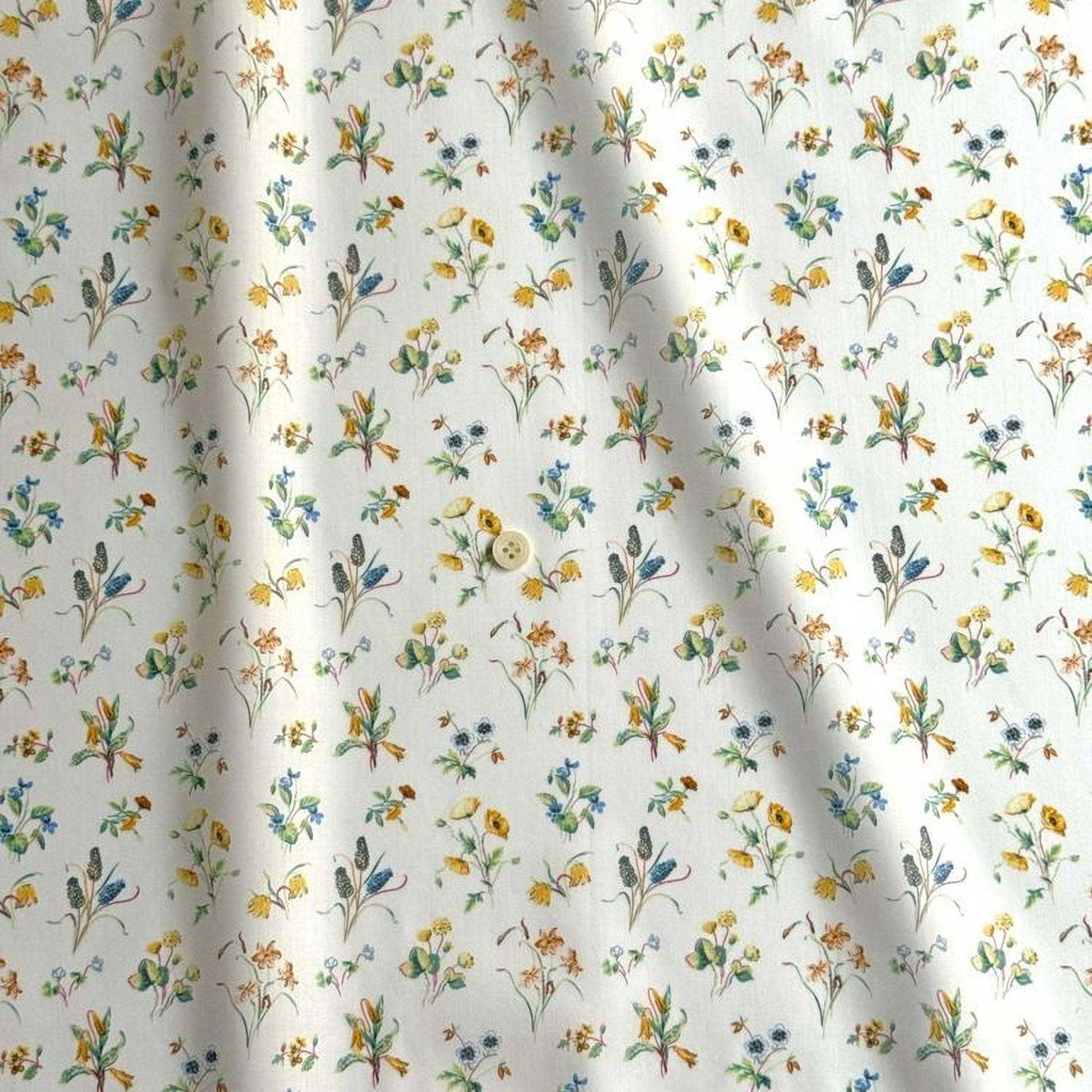 a close-up view of a fabric with a repeating floral pattern in various colors, including yellow, orange, and green. The pattern consists of small flowers and leaves, creating a visually appealing and intricate design.