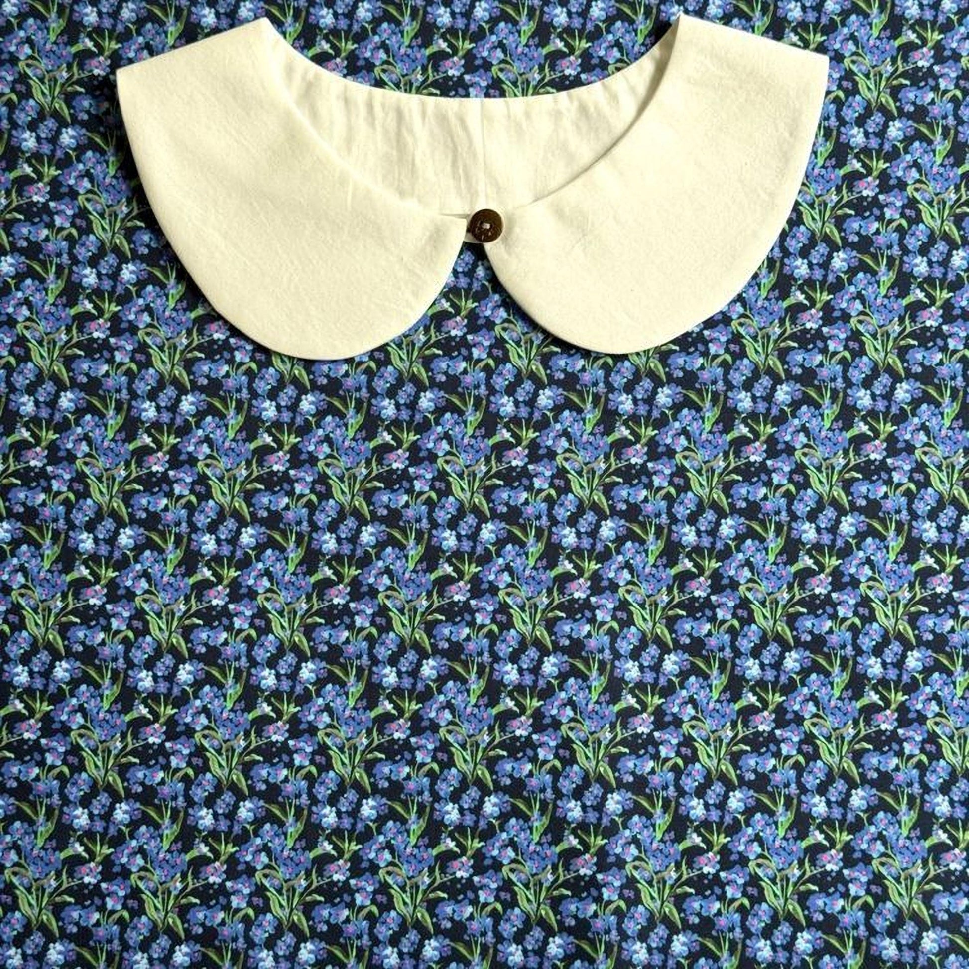 a white collar with a button, set against a background of a blue floral print.