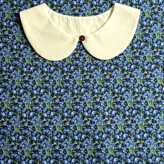 a white collar with a button, set against a background of a blue floral print.