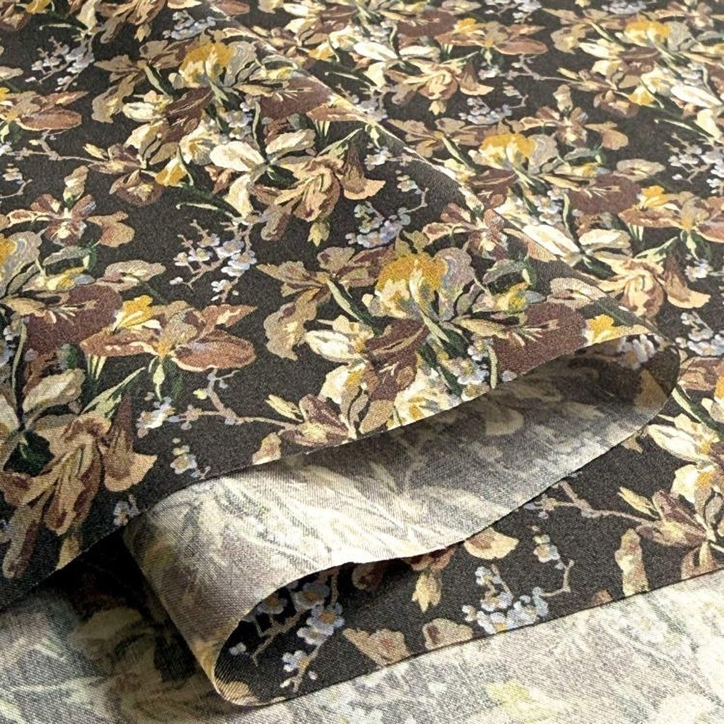a close-up view of a fabric with a floral pattern, featuring a mix of brown, yellow, and white colors. The fabric appears to be made of a material with a textured surface, giving it a unique and visually appealing appearance.