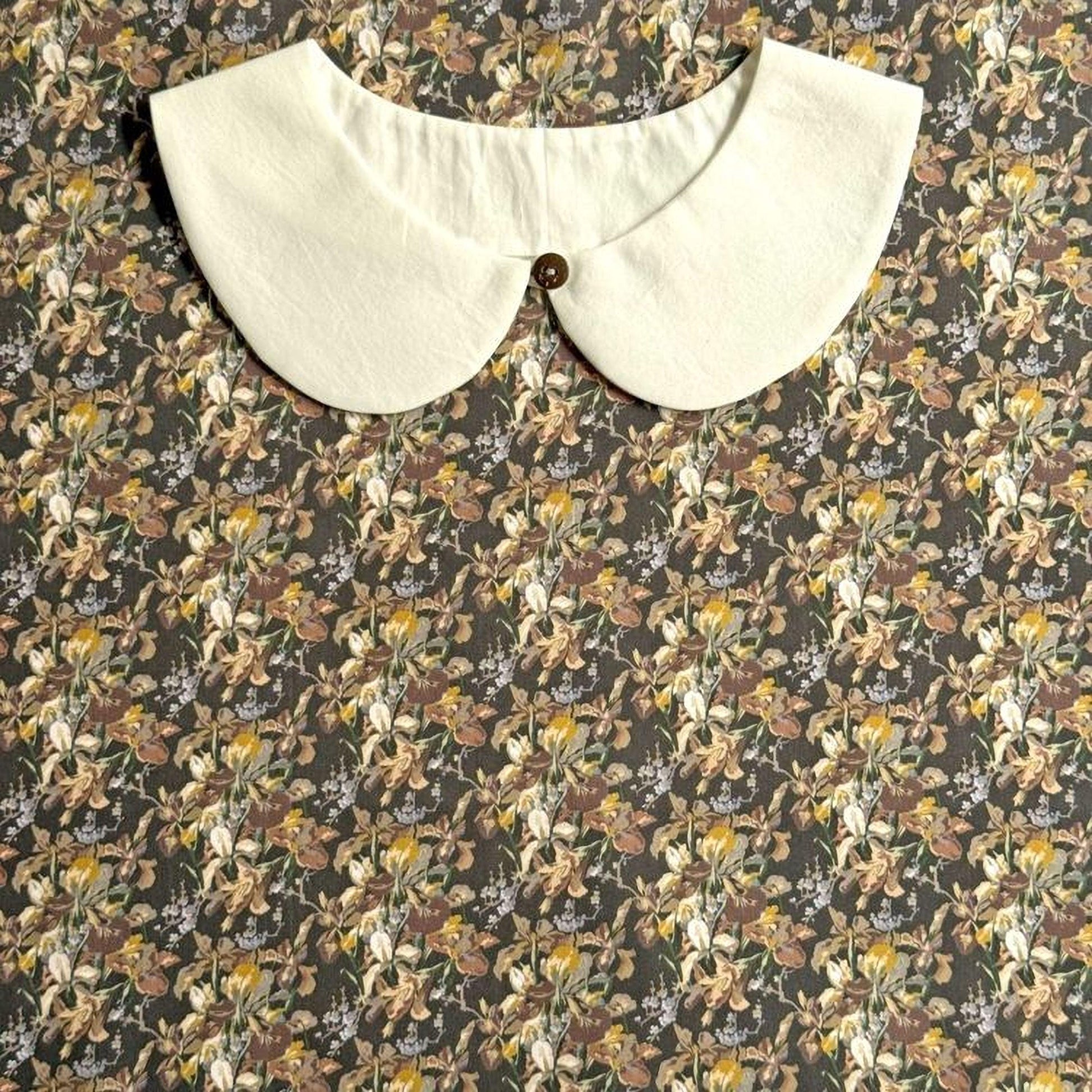 A white collar is displayed against a floral print background.