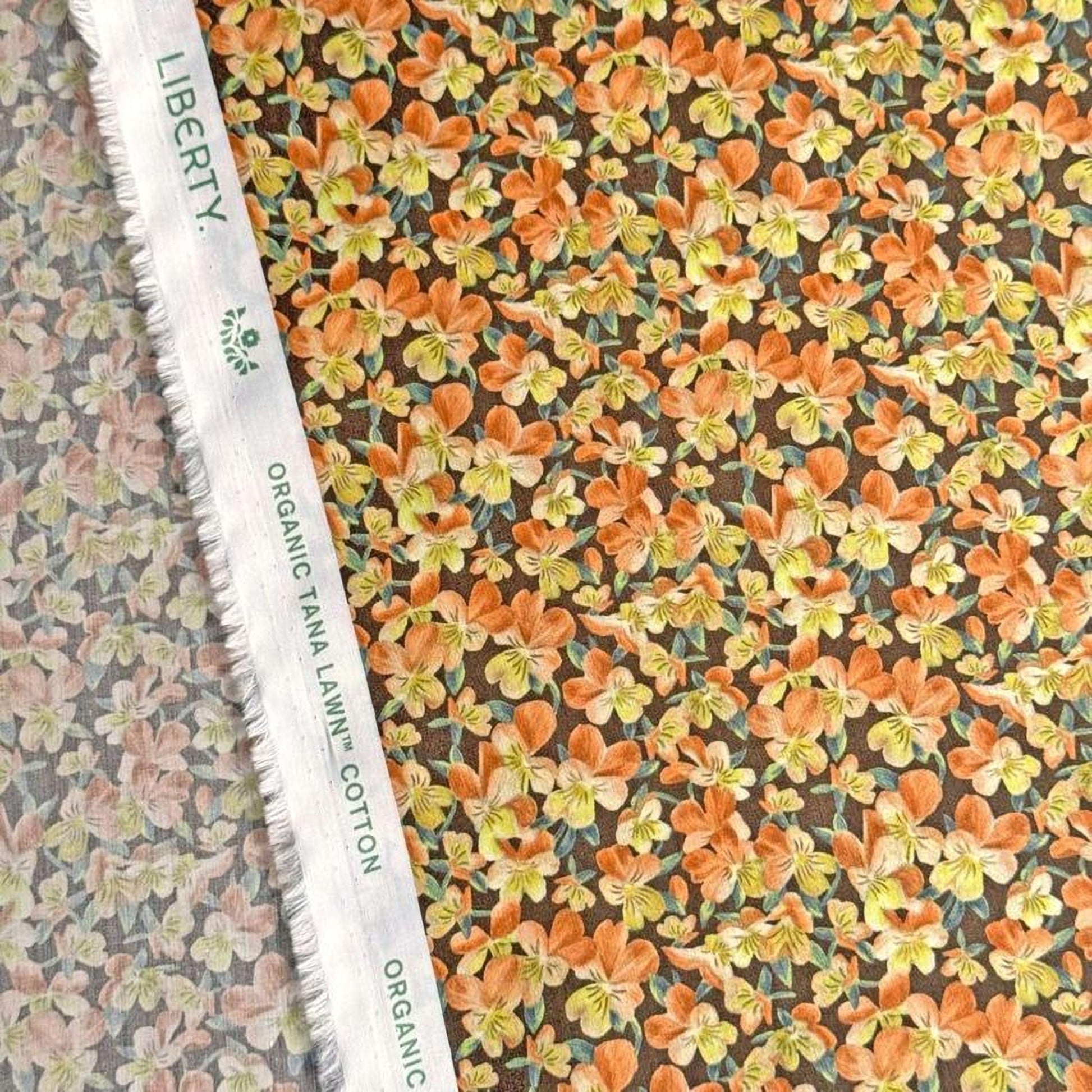 a close-up view of a fabric with a floral pattern, including orange and yellow flowers. The fabric appears to be made of cotton and is displayed on a white fabric ruler.