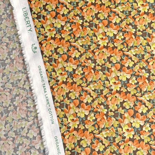 a close-up view of a fabric with a floral pattern, including orange and yellow flowers. The fabric appears to be made of cotton and is displayed on a white fabric ruler.