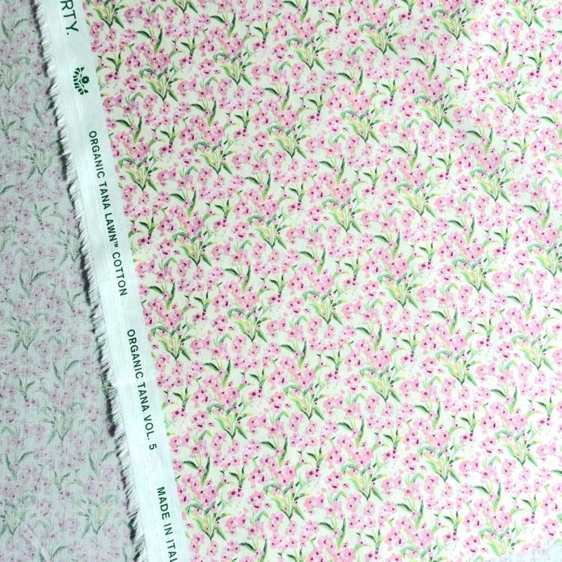 a close-up view of a fabric with a floral pattern in shades of pink and green. The fabric appears to be made of cotton and has a white label with text on it.