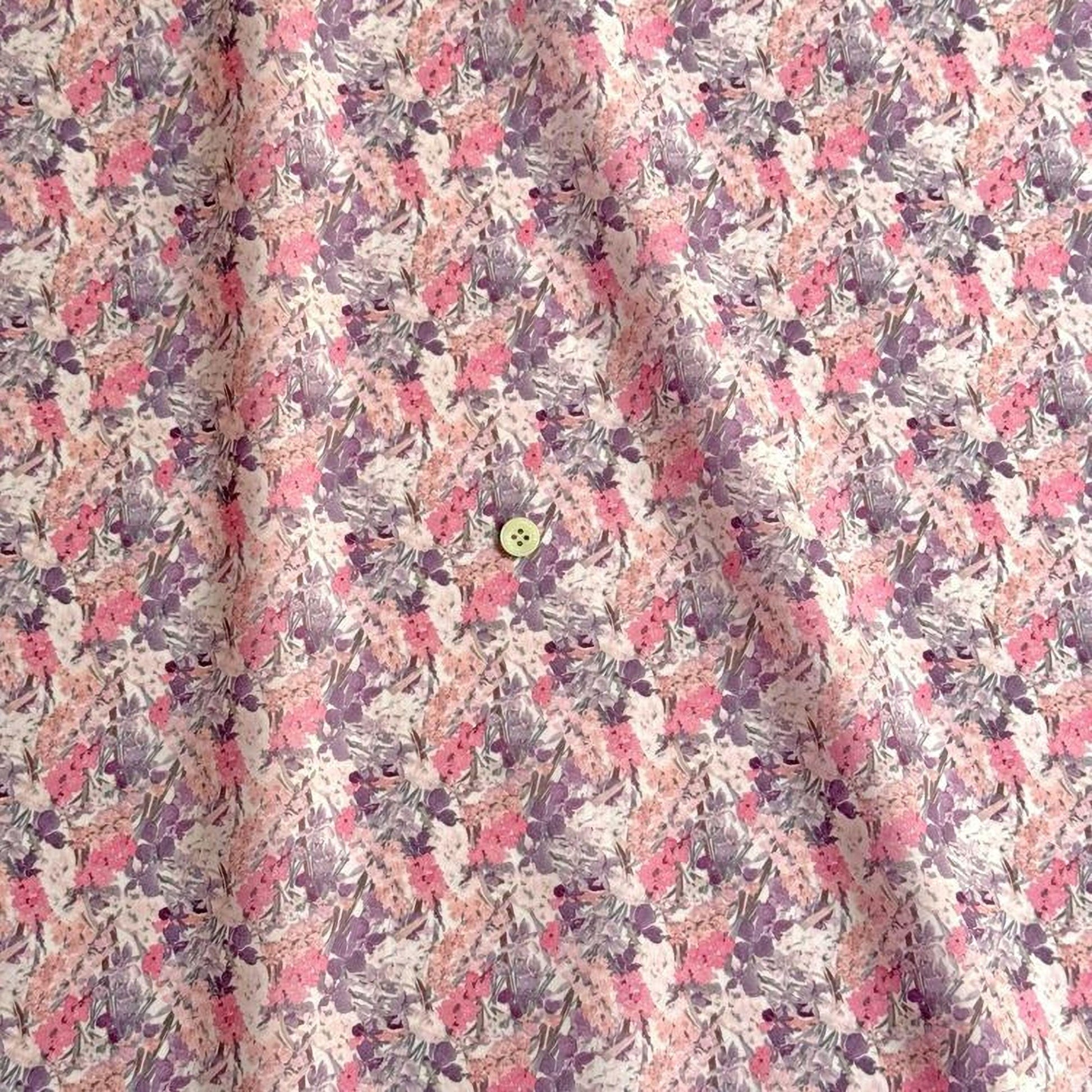 a close-up view of a fabric with a floral pattern in shades of pink and purple. There is a small button visible in the center of the fabric.