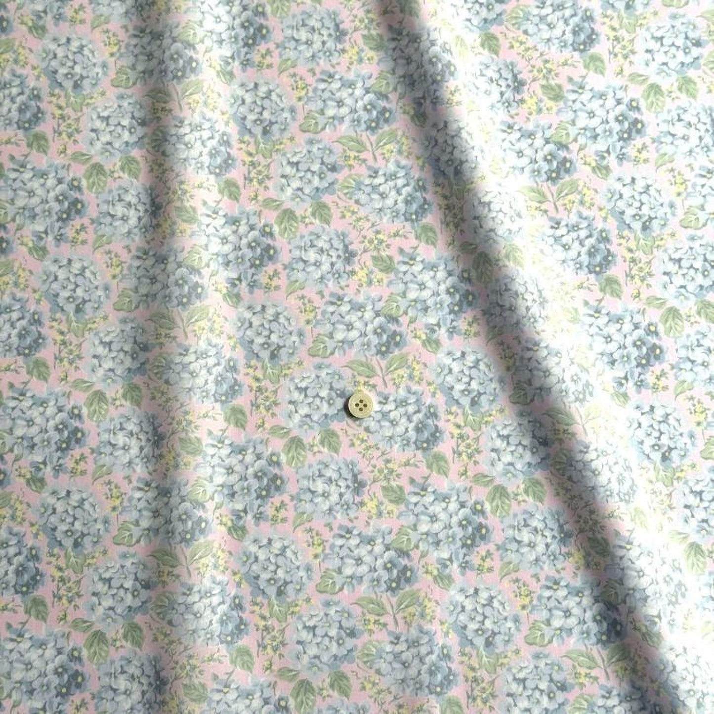 a close-up view of a fabric with a floral pattern, featuring a small button in the center.