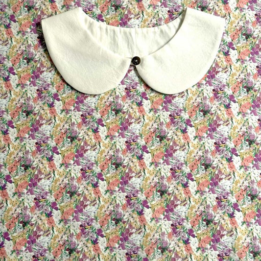a white collar with a button, placed on a floral print fabric.