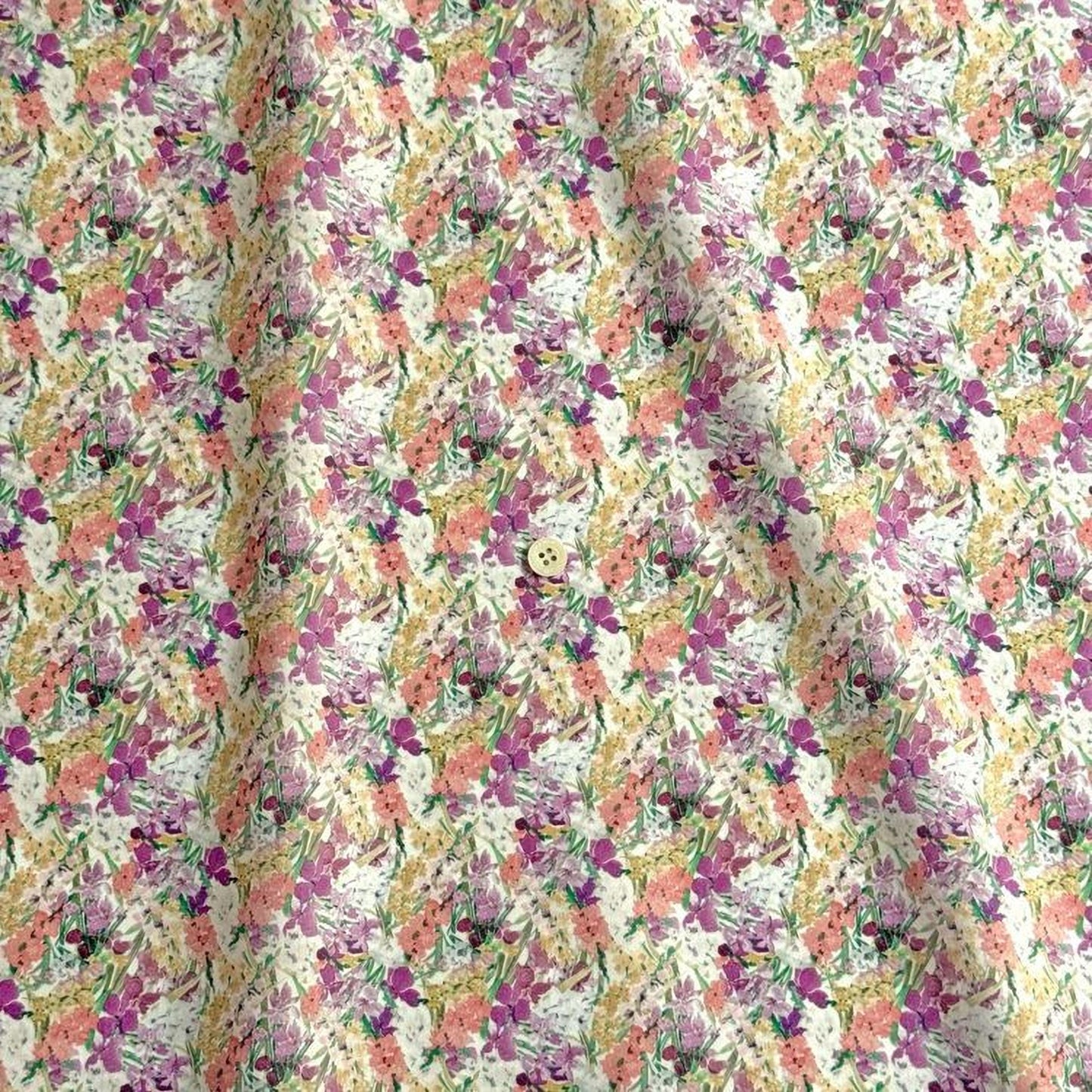 a fabric with a repeating floral pattern in shades of pink, yellow, and white. The pattern is composed of various flowers and leaves, creating a visually appealing and vibrant design.