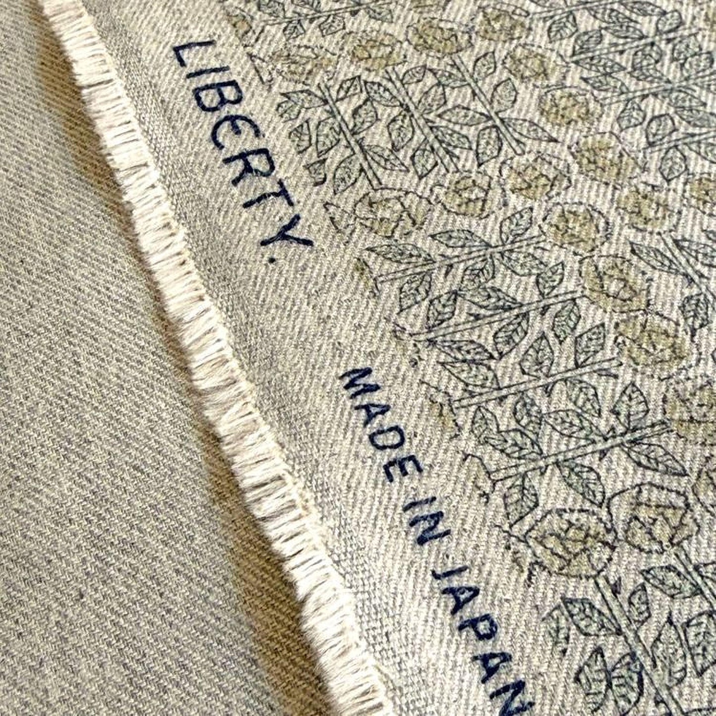a close-up view of a fabric with a floral pattern, featuring the text "LIBERTY" and "MADE IN JAPAN" printed on it.