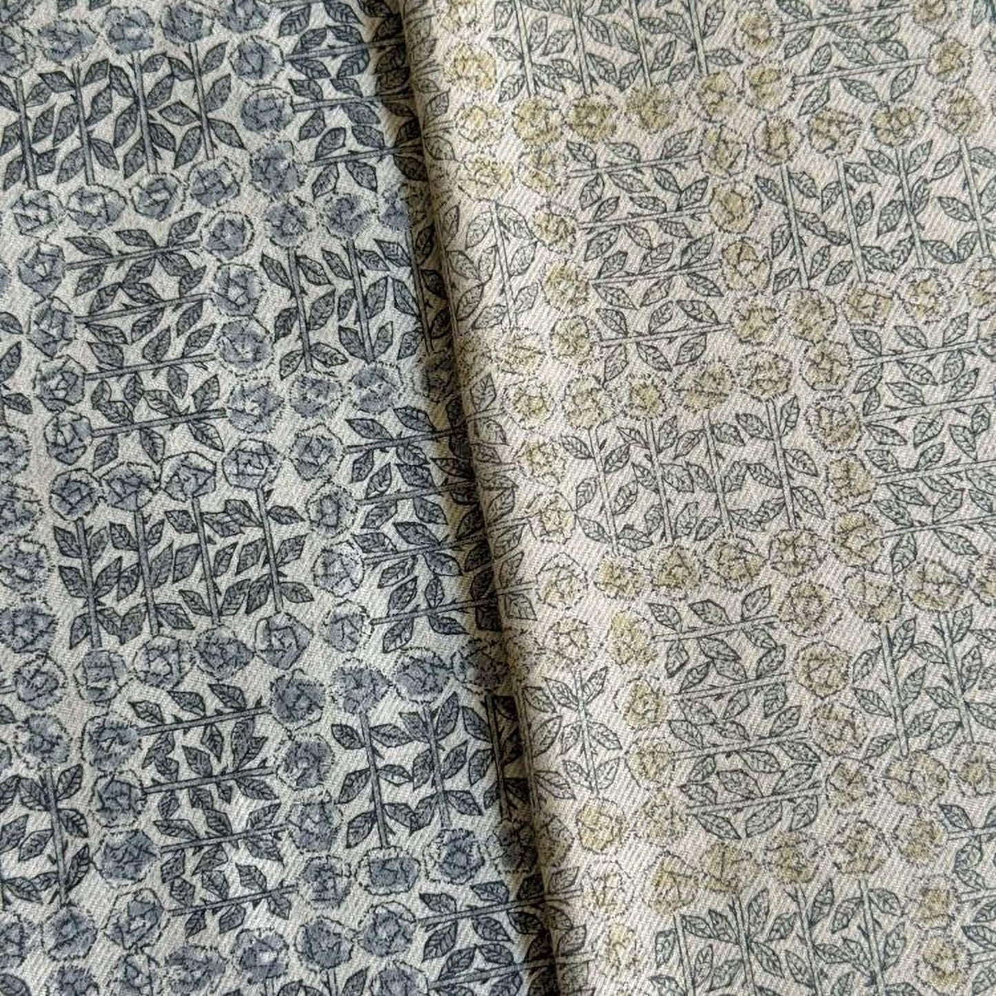 two fabric swatches with a repeating pattern of leaves and flowers in shades of gray and beige.