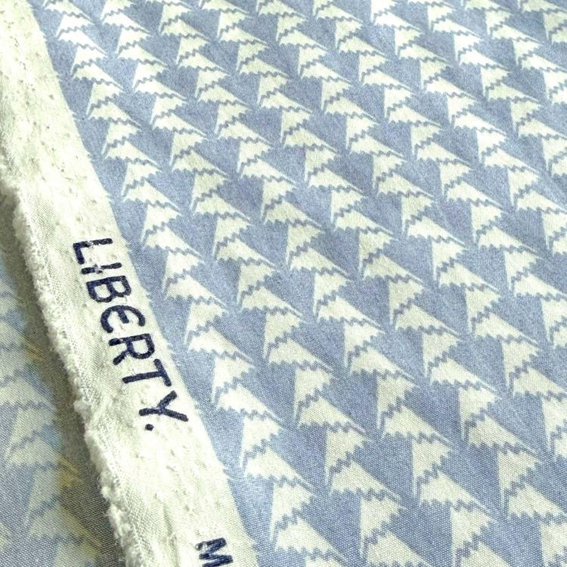 a close-up view of a fabric with a repeating pattern of white triangles on a blue background.