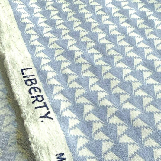 a close-up view of a fabric with a repeating pattern of white triangles on a blue background.
