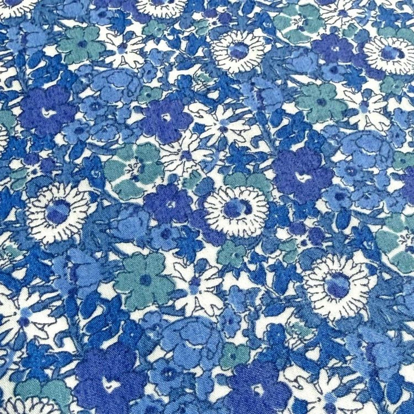 The image is a close-up of a fabric with a blue and white floral pattern. The fabric appears to be a textile or material with a repeating floral design in shades of blue and white.