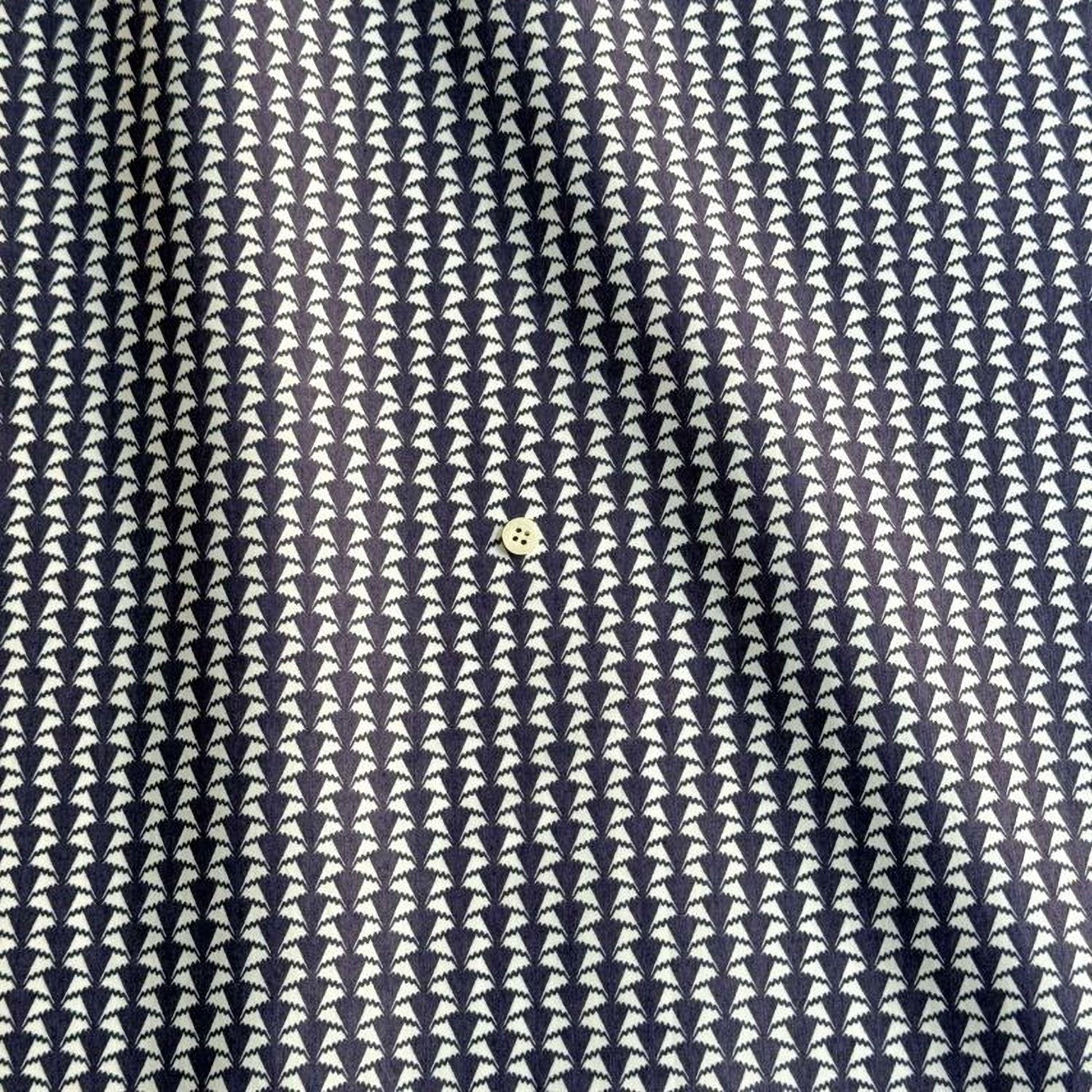 a close-up view of a fabric with a repeating pattern of white triangles arranged in a diagonal grid. The fabric appears to be dark blue, and there is a small white button visible in the center of the pattern.
