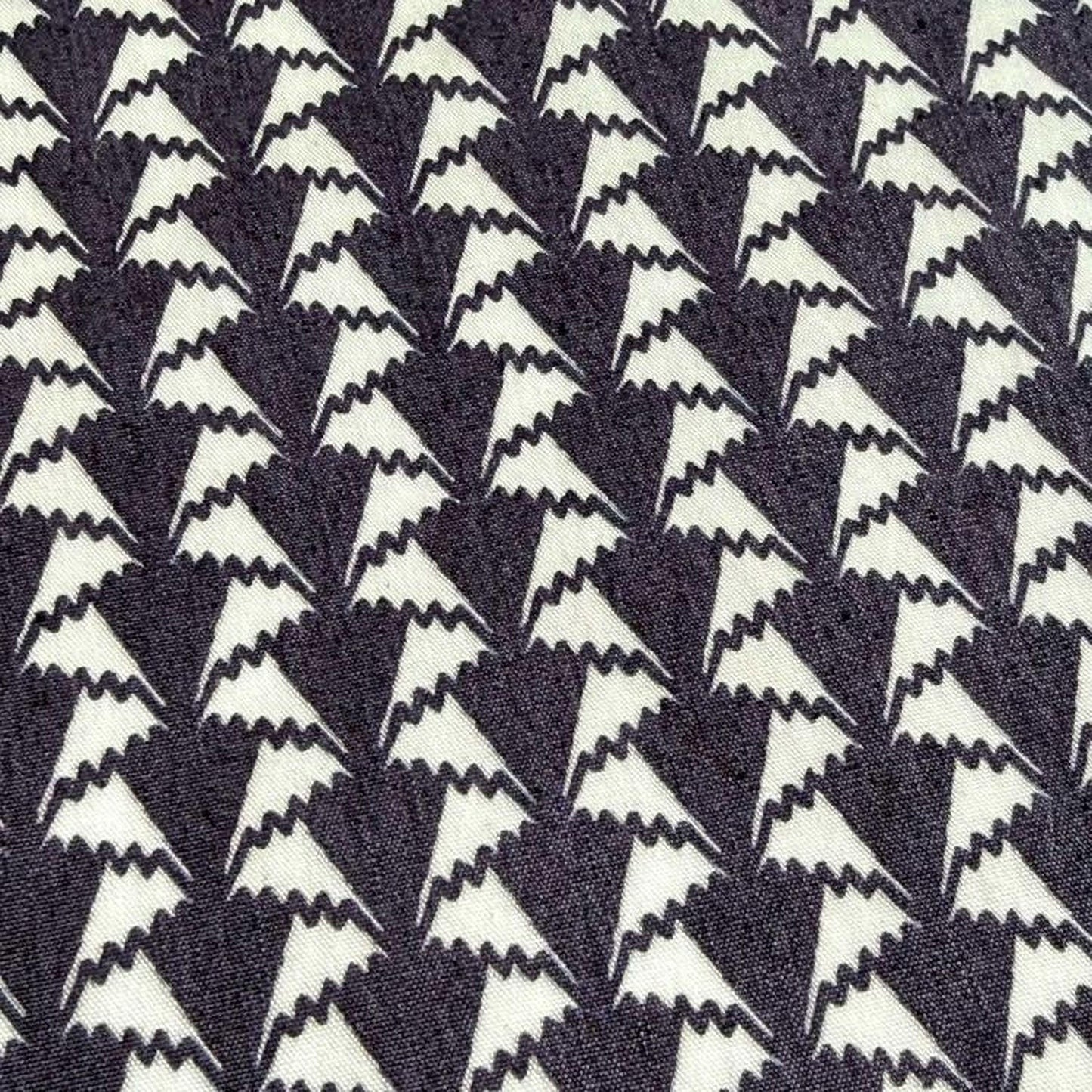 a close-up view of a fabric with a repeating pattern of white triangles on a dark background.