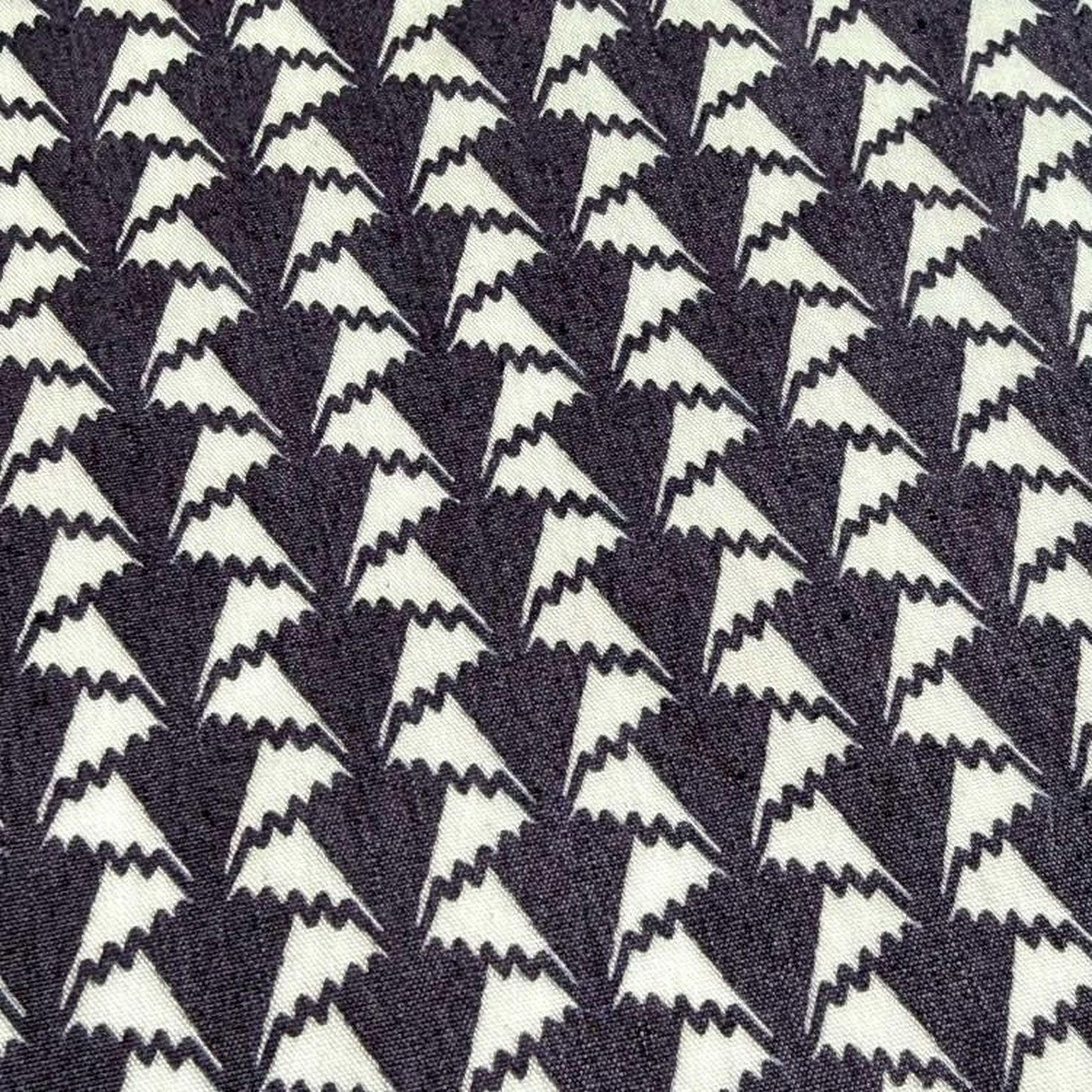 a close-up view of a fabric with a repeating pattern of white triangles on a dark background.