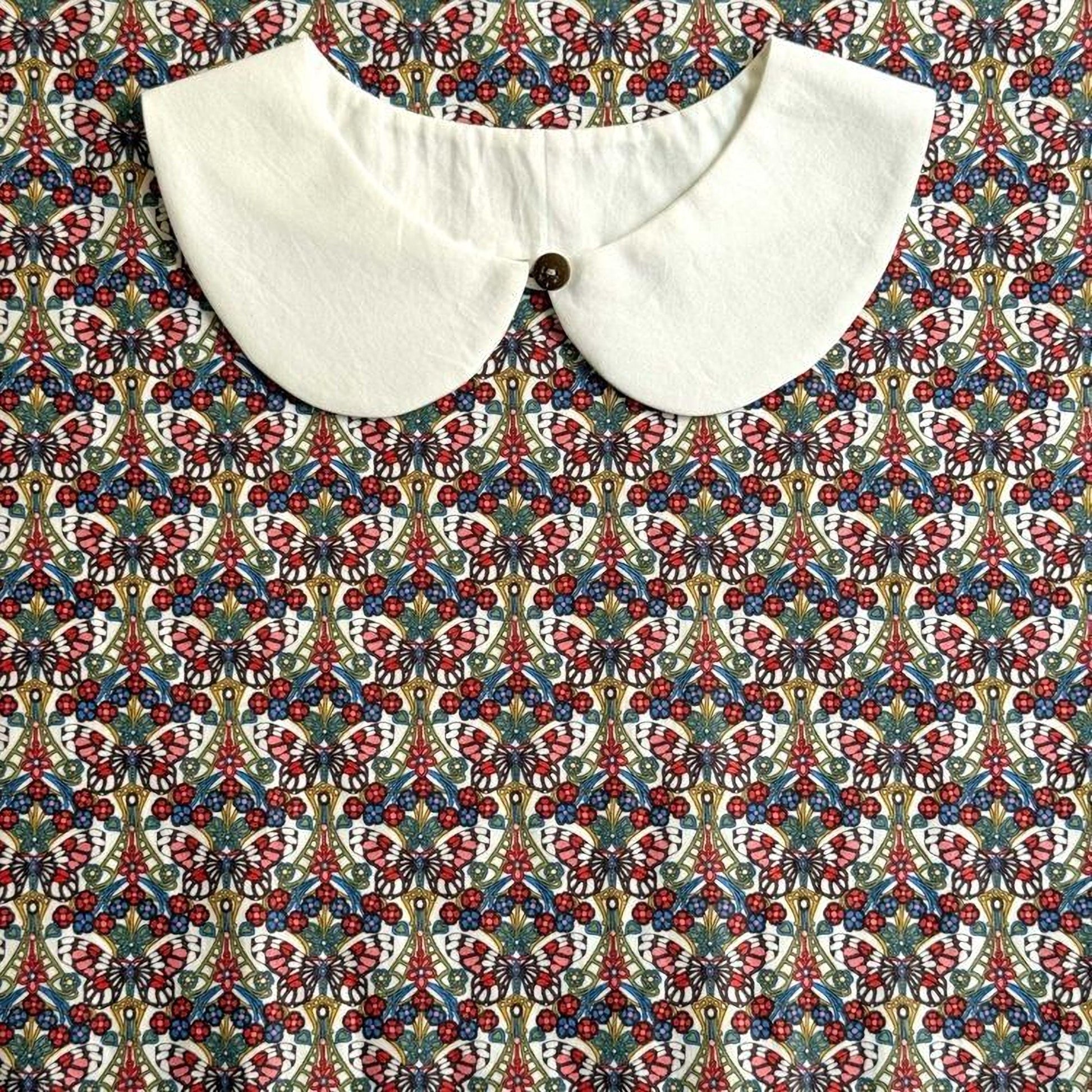 a white collar with a button, set against a colorful, patterned fabric background.