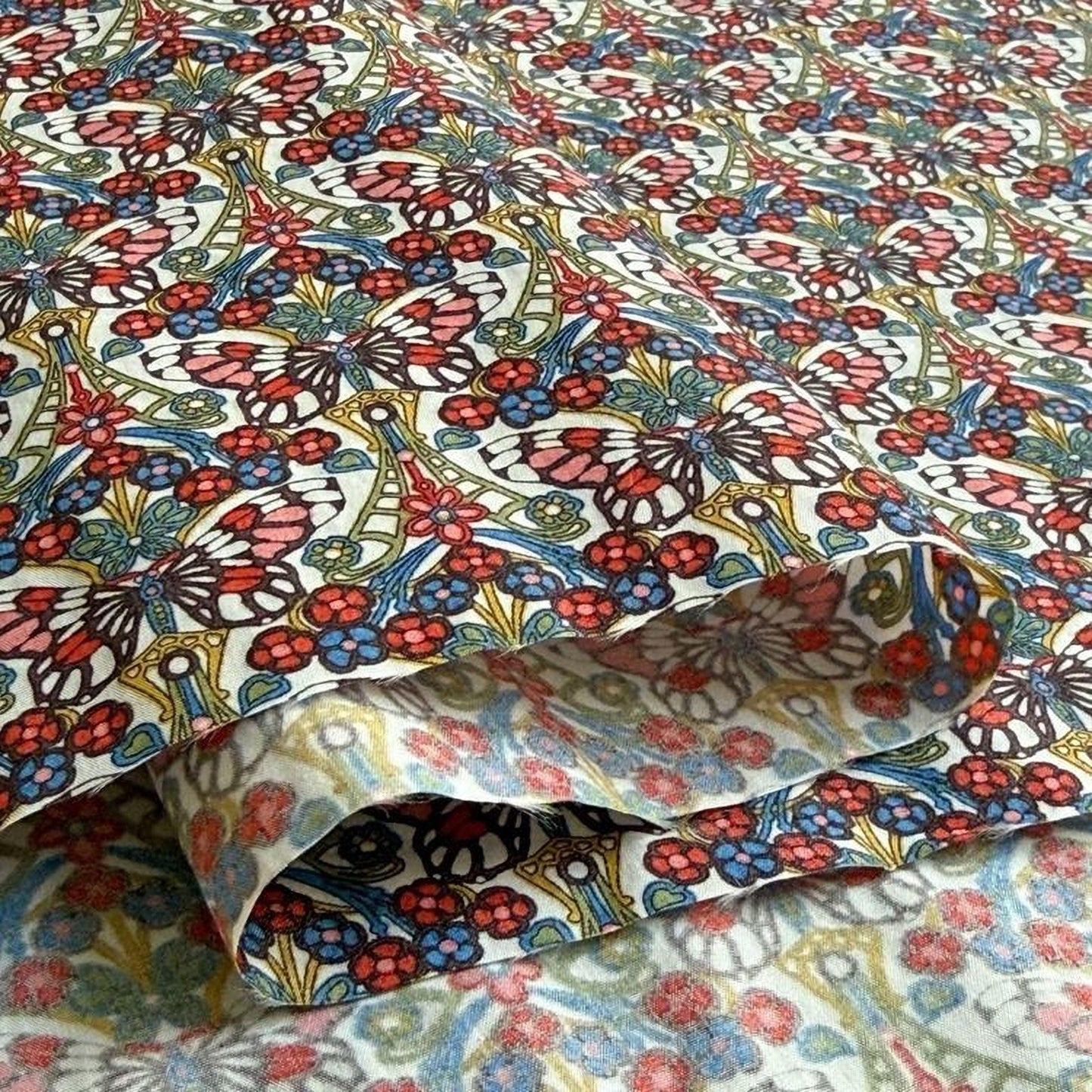 a close-up view of a fabric with a vibrant, colorful floral pattern. The pattern consists of various flowers and butterflies in shades of red, blue, green, and yellow, creating a visually striking and intricate design.