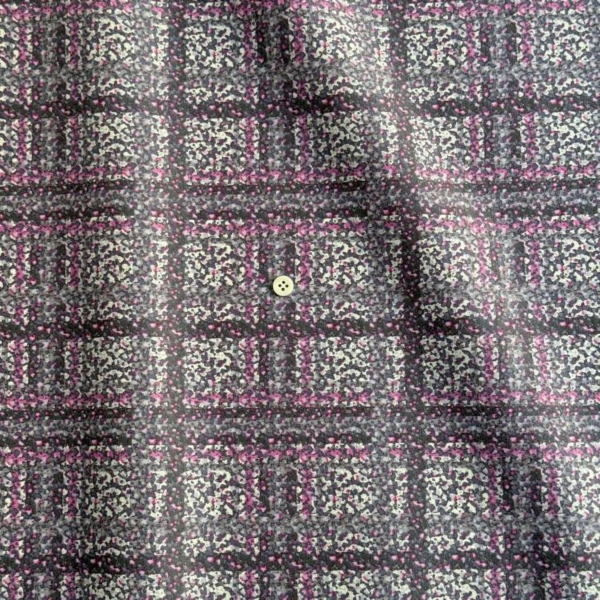 a close-up view of a fabric with a pattern of small squares in shades of pink and gray, creating a checkered or plaid design. There is a small button visible in the center of the pattern.
