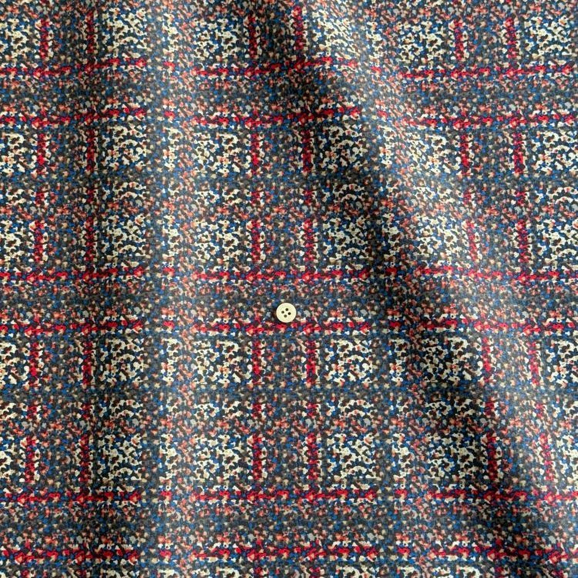 a close-up view of a fabric with a colorful, abstract pattern of small squares in various shades of blue, red, and white. There is a small button visible in the center of the pattern.