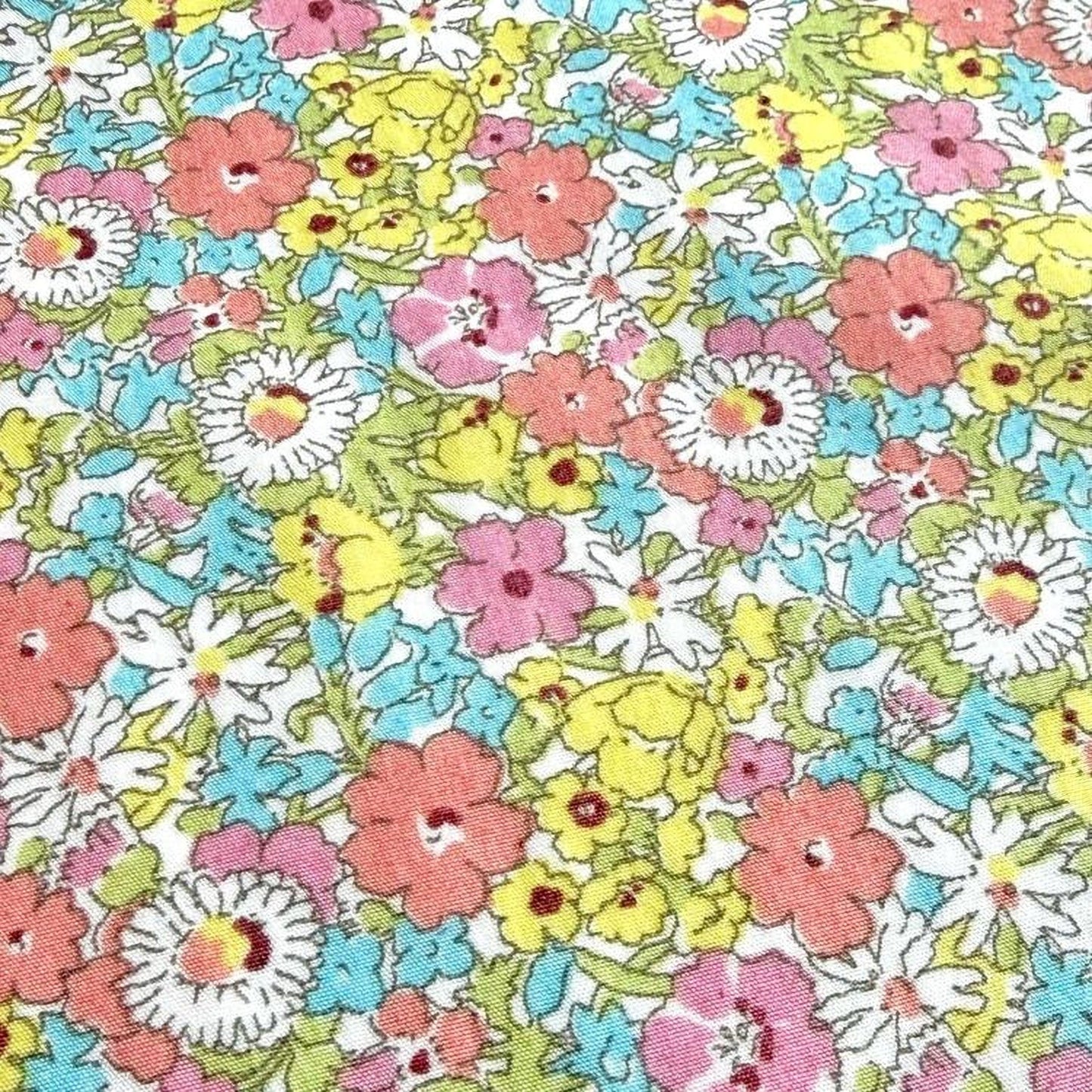 The image is a close-up of a fabric with a vibrant floral pattern, featuring a variety of colorful flowers in shades of pink, yellow, and white.