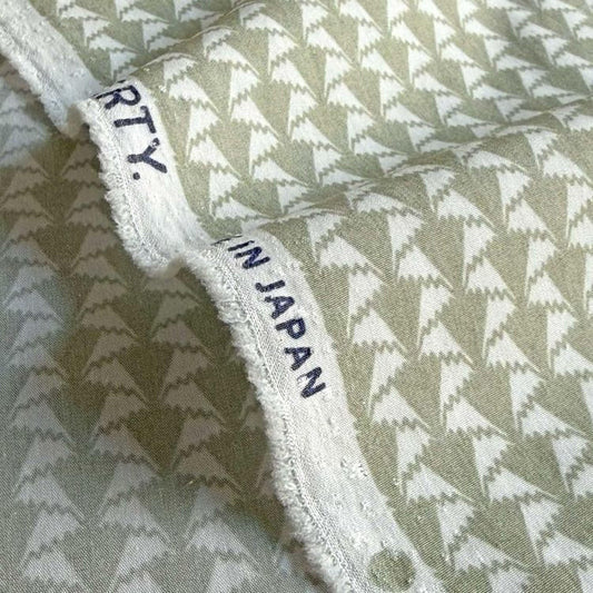 a close-up view of a fabric with a repeating pattern of white triangles on a beige background.