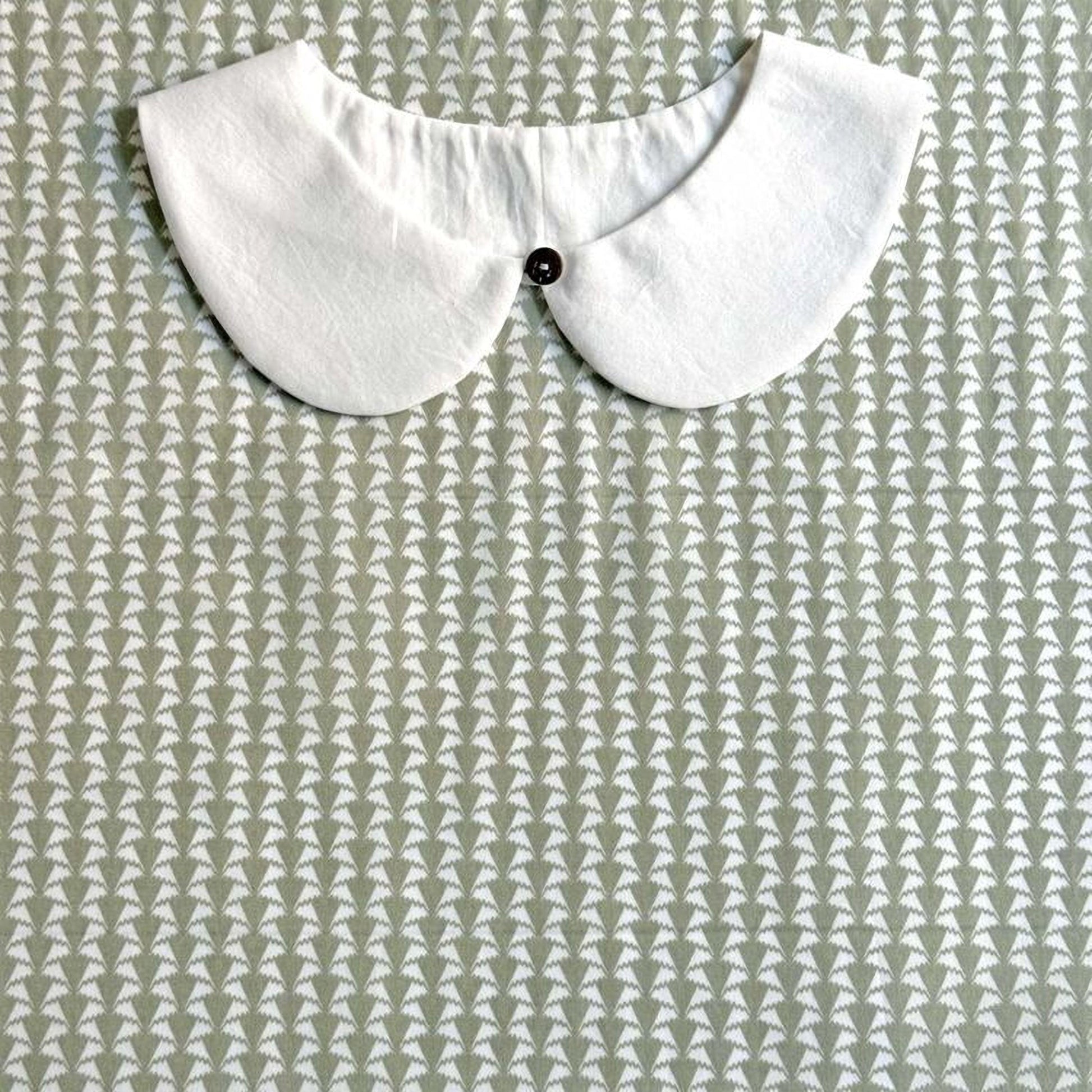 A white collar is displayed against a patterned fabric background.