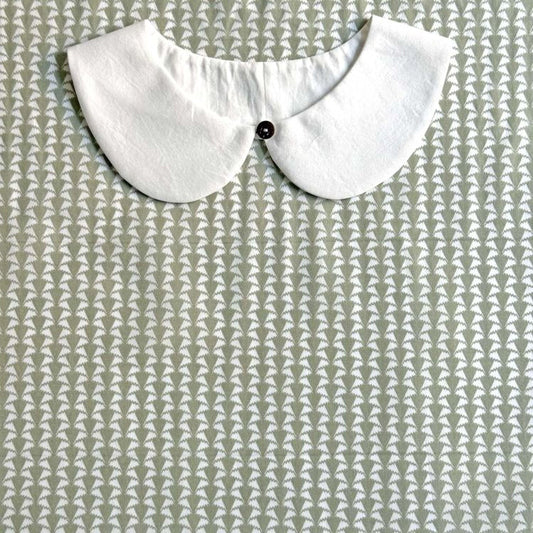 A white collar is displayed against a patterned fabric background.