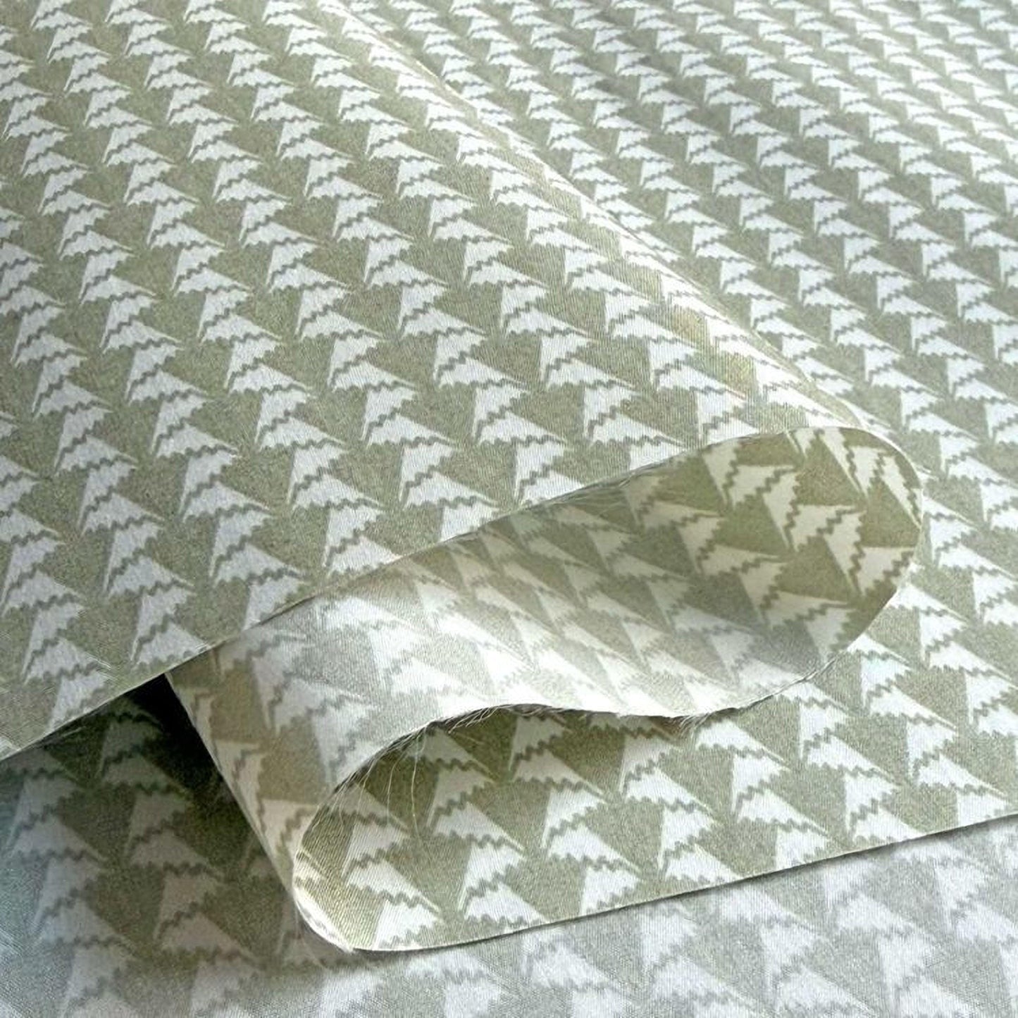 a close-up view of a patterned fabric or paper with a repeating geometric design in shades of green and white.