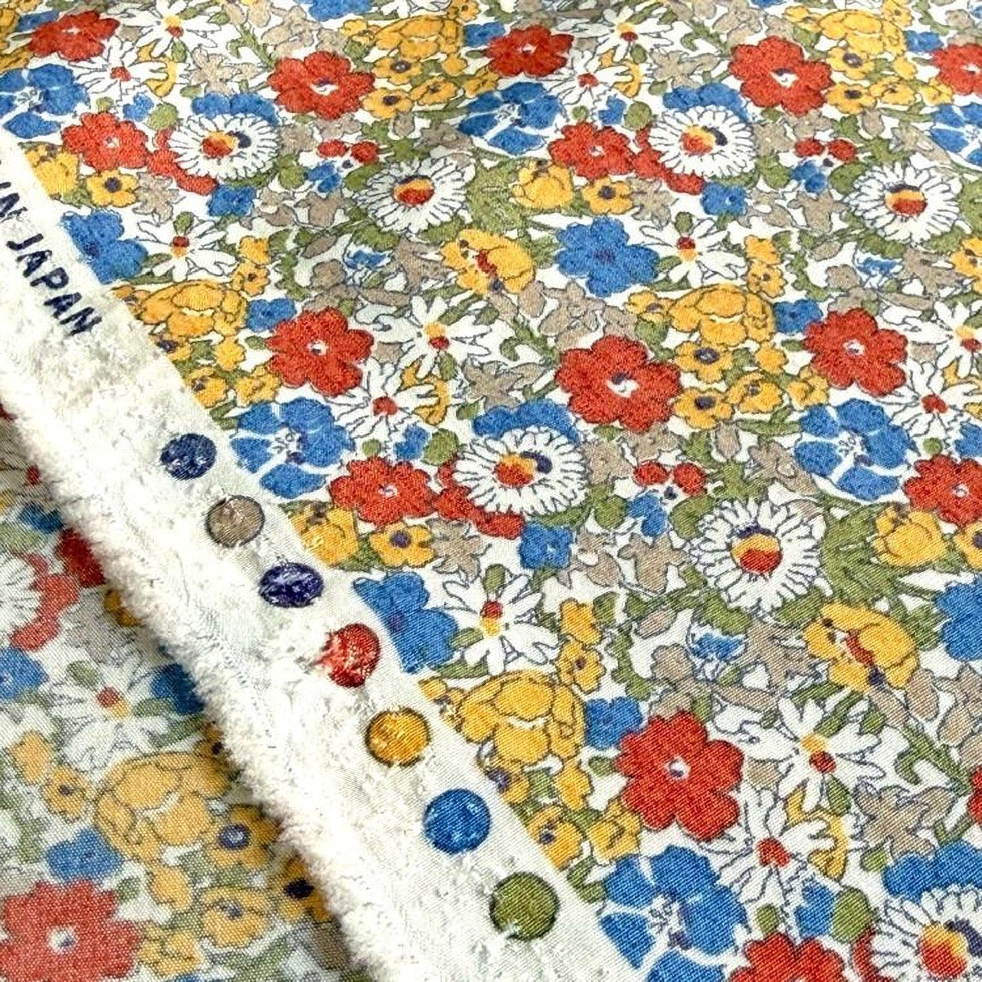 a close-up view of a fabric with a vibrant floral pattern in various colors, including red, yellow, blue, and white. The fabric appears to be a piece of Japanese-style fabric, as indicated by the text "JAPAN" visible in the image.