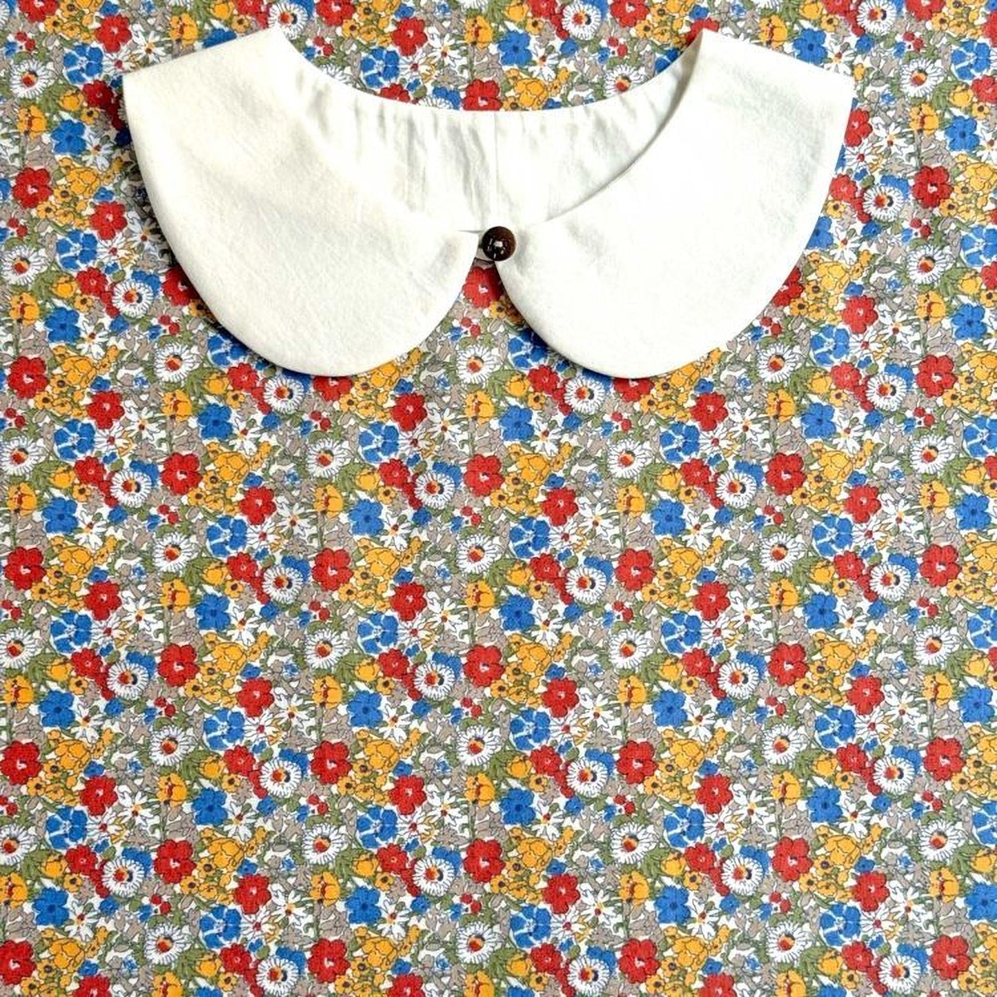 A white collar is displayed against a colorful floral background.