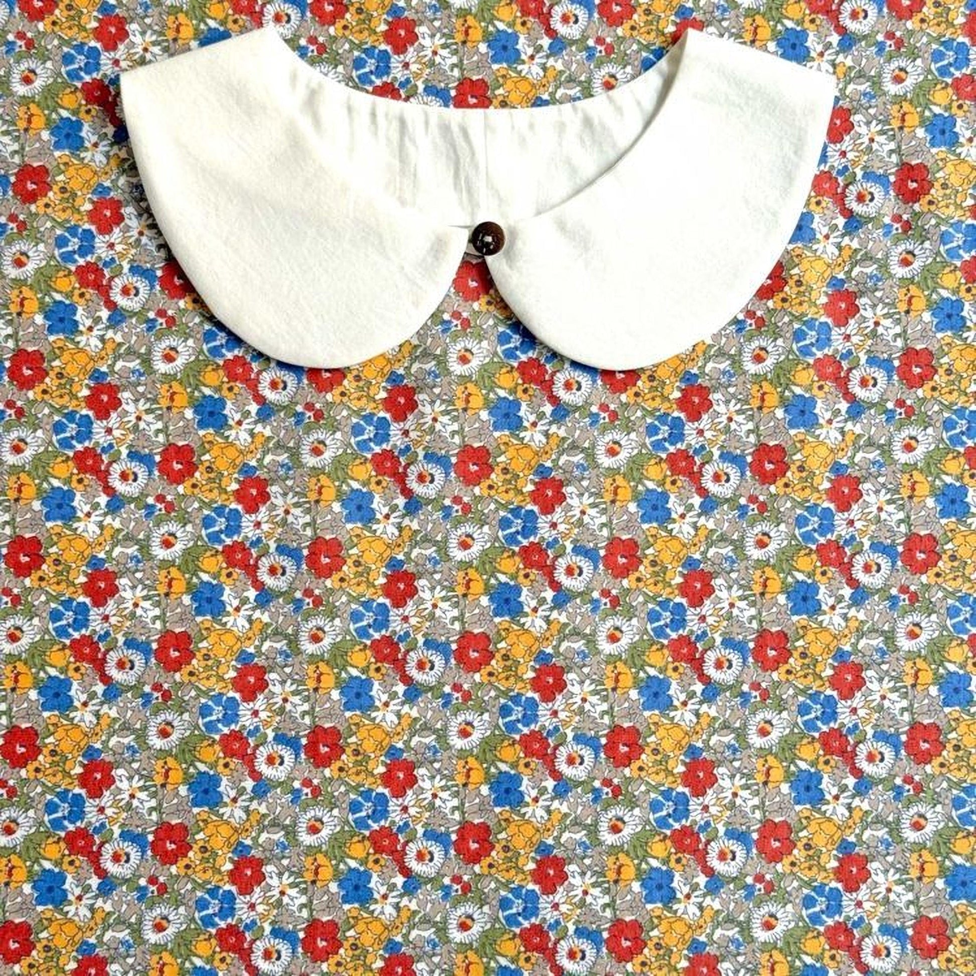 A white collar is displayed against a colorful floral background.