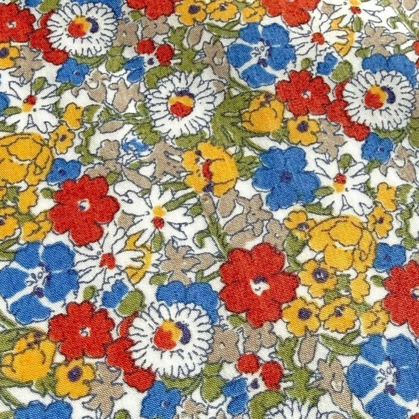 The image is a close-up of a fabric with a vibrant floral pattern, featuring a variety of colorful flowers in shades of red, yellow, blue, and white.