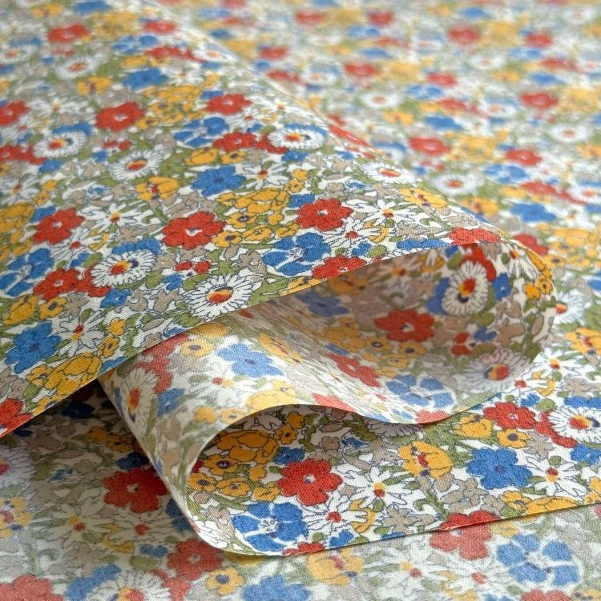 a close-up view of a colorful, floral-patterned fabric, with a variety of red, yellow, and blue flowers and leaves.