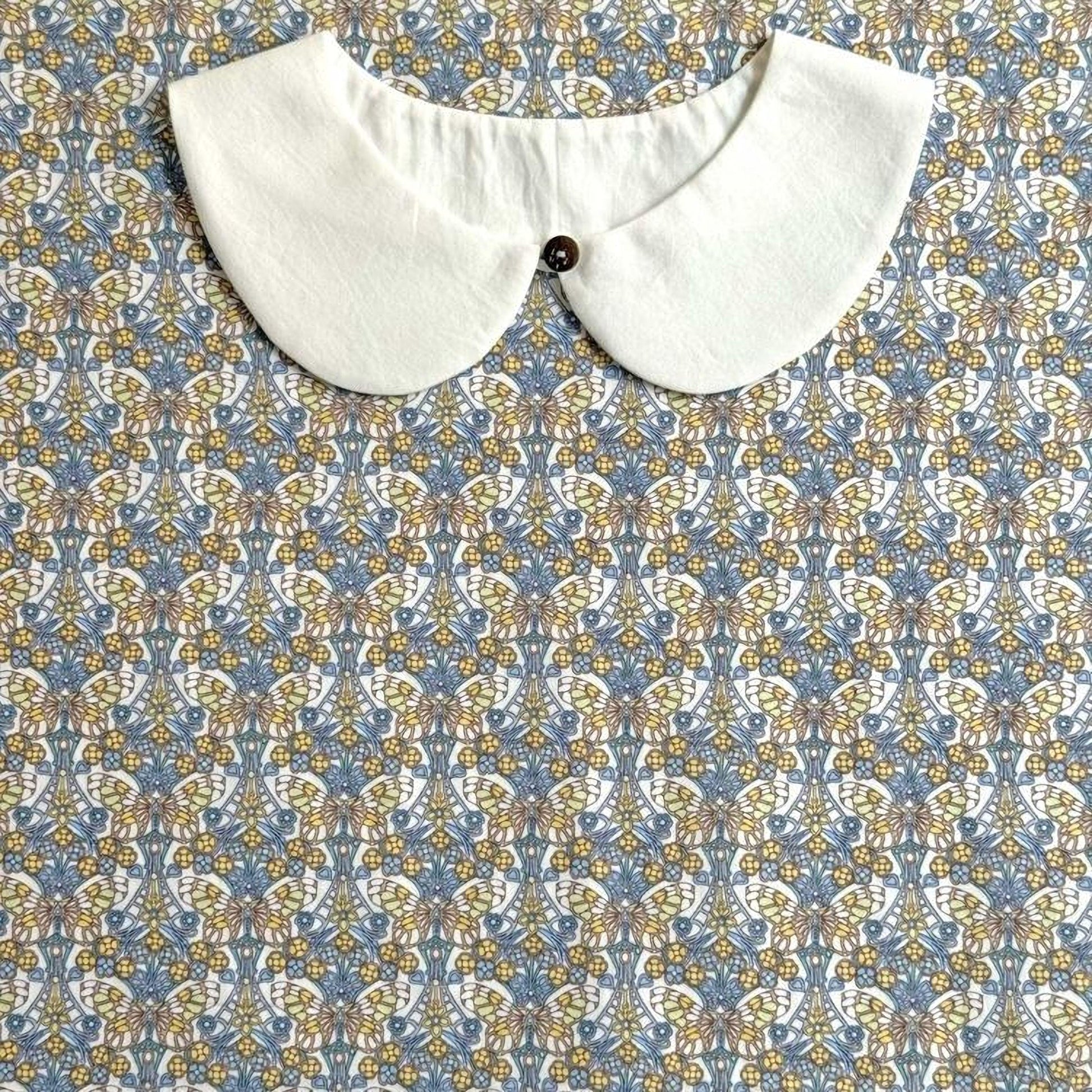 A white collar is displayed against a patterned fabric background.