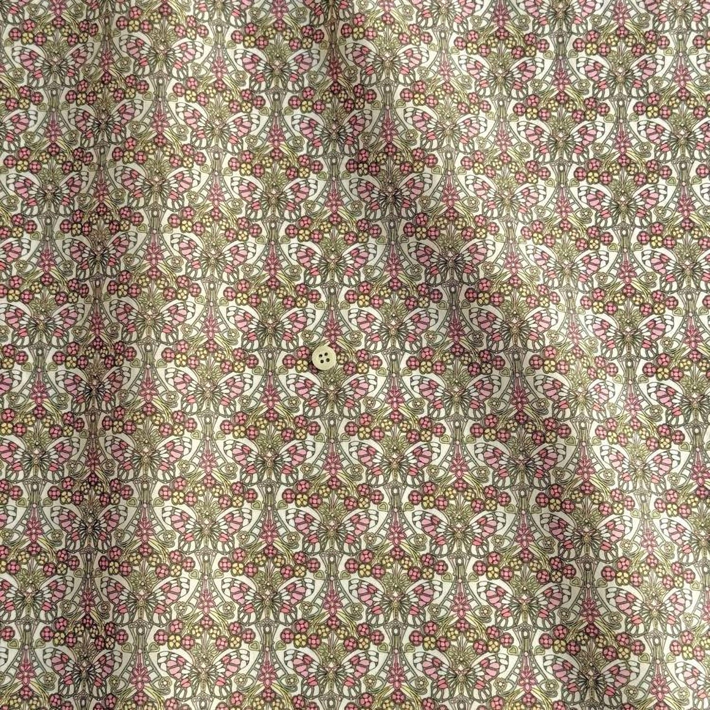 a repeating pattern of a floral design in shades of pink and green, with a small button visible in the center.