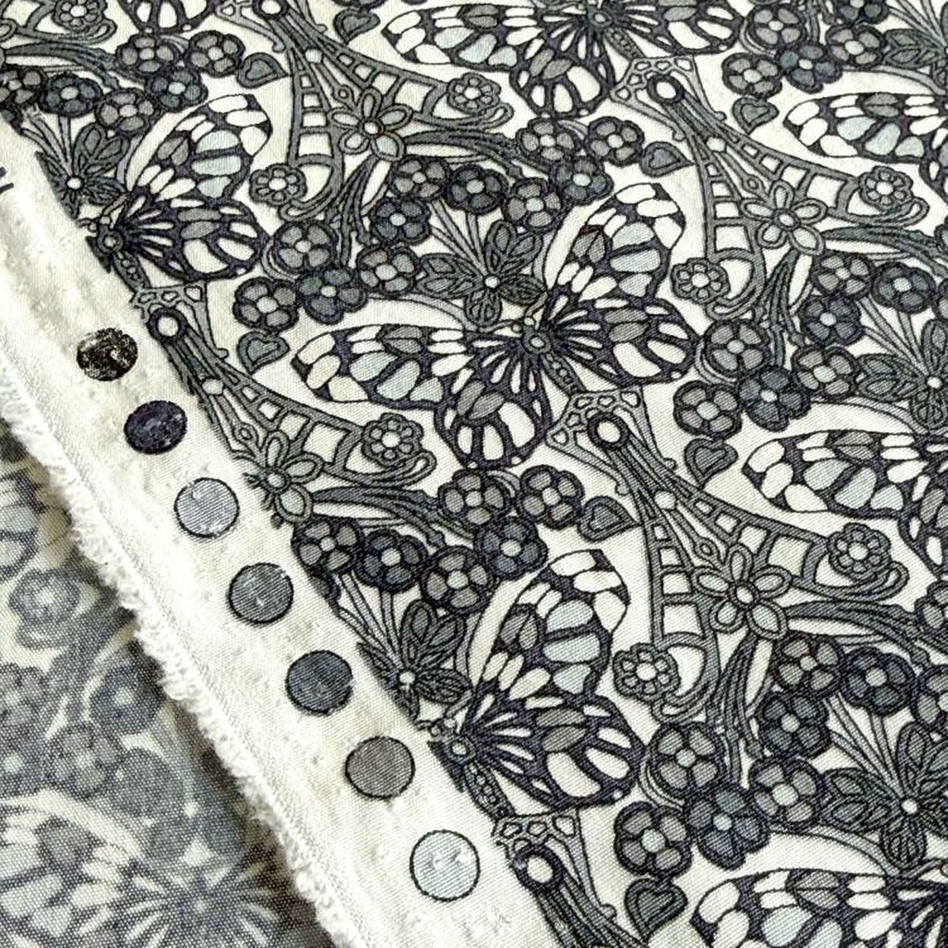 a close-up view of a fabric with a black and white butterfly pattern. The fabric appears to be a piece of clothing or textile, with a decorative design of butterflies and flowers.