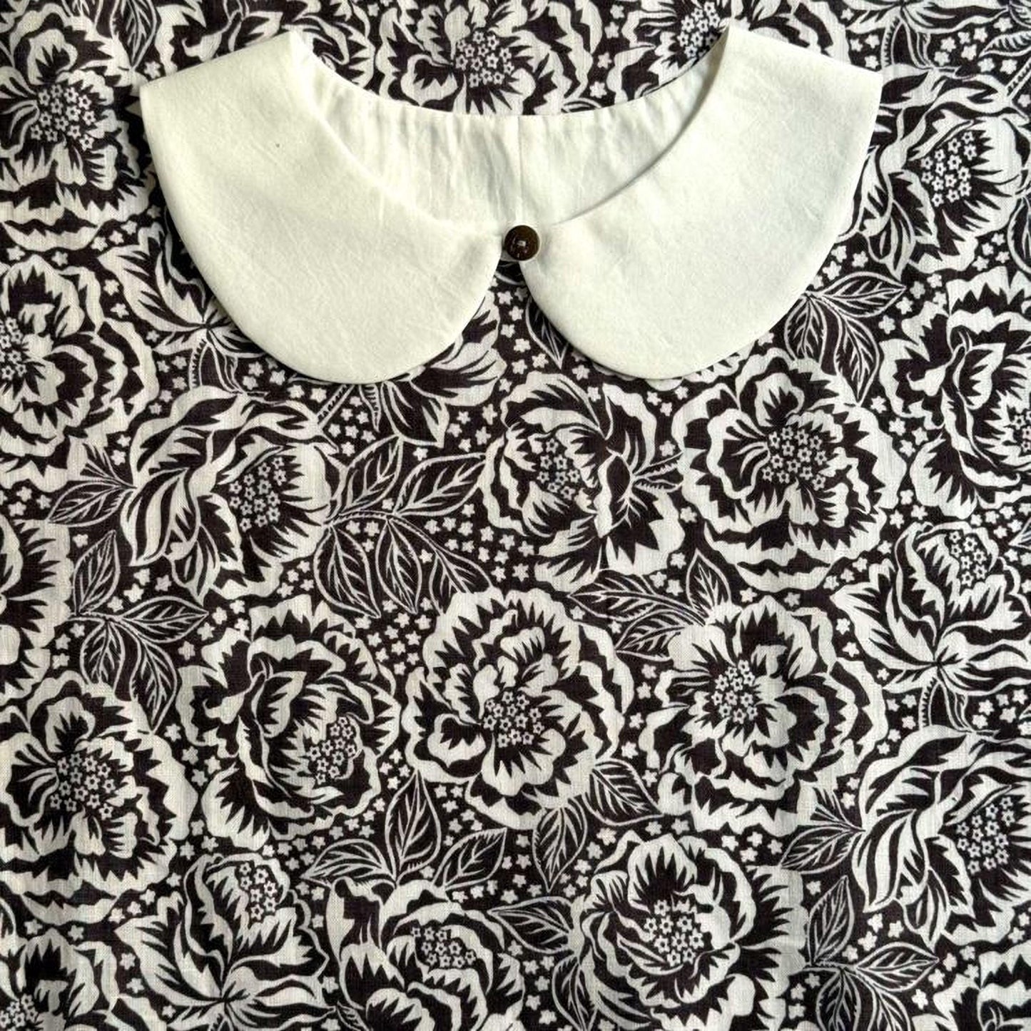 a close-up view of a white collar on a black and white floral patterned fabric.