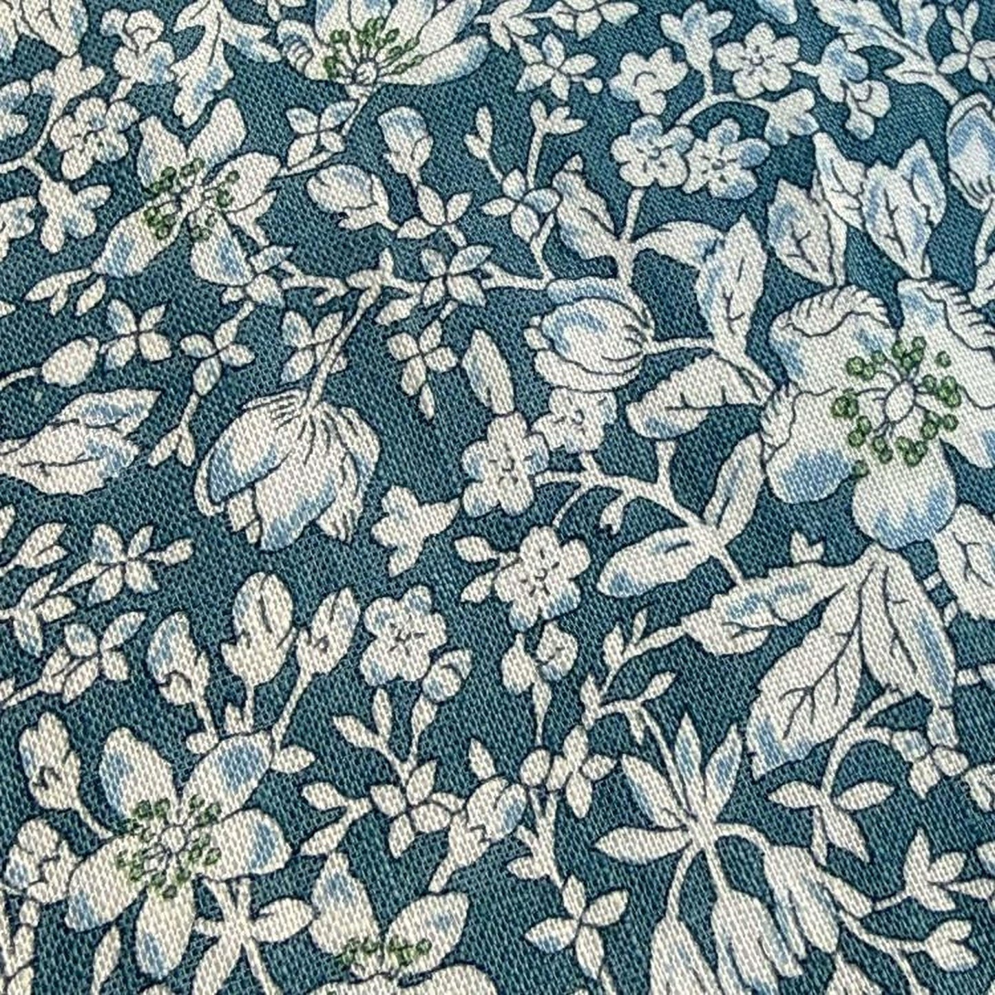 a close-up view of a fabric with a floral pattern in shades of blue and white. The pattern consists of various flowers and leaves, creating a visually appealing and intricate design.