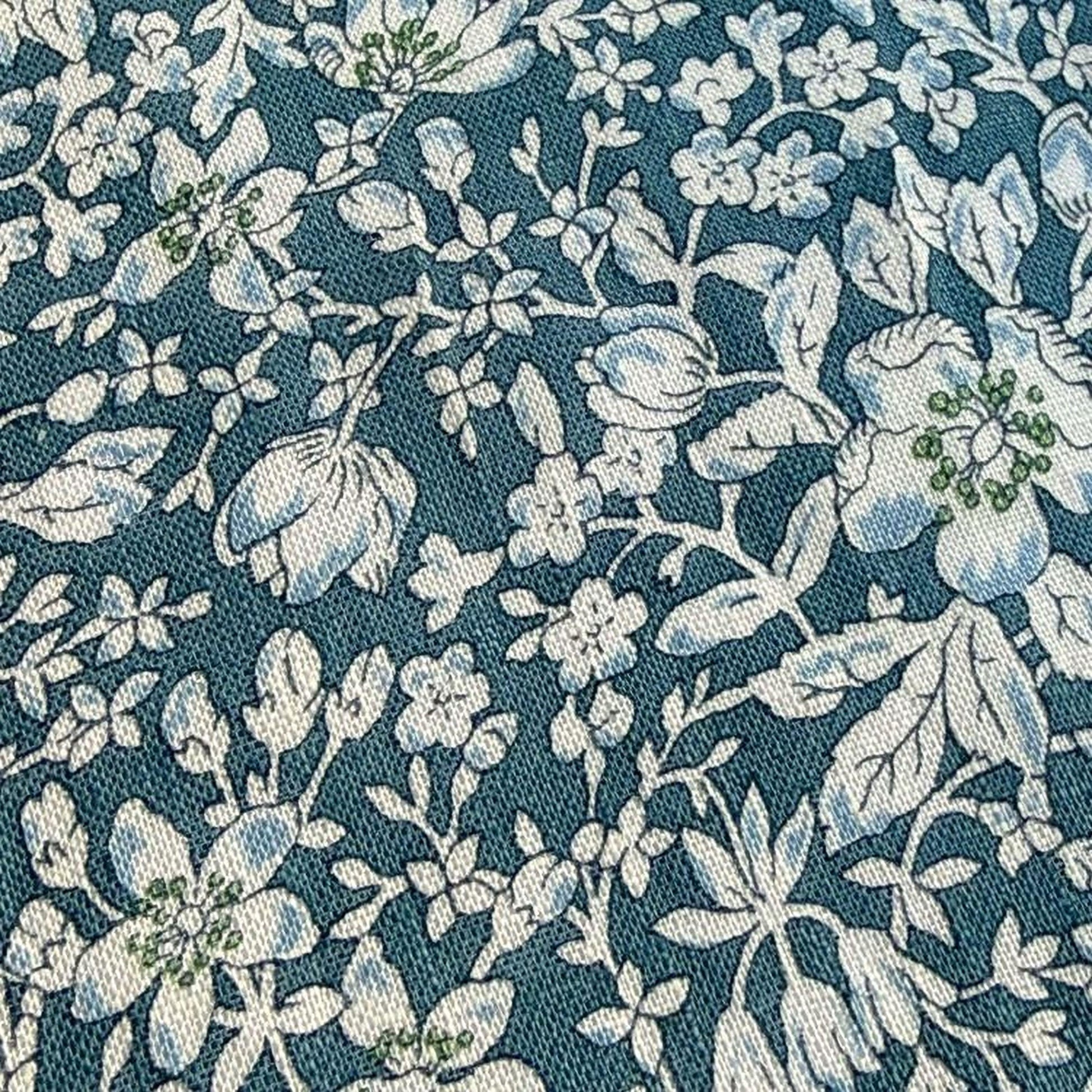 a close-up view of a fabric with a floral pattern in shades of blue and white. The pattern consists of various flowers and leaves, creating a visually appealing and intricate design.