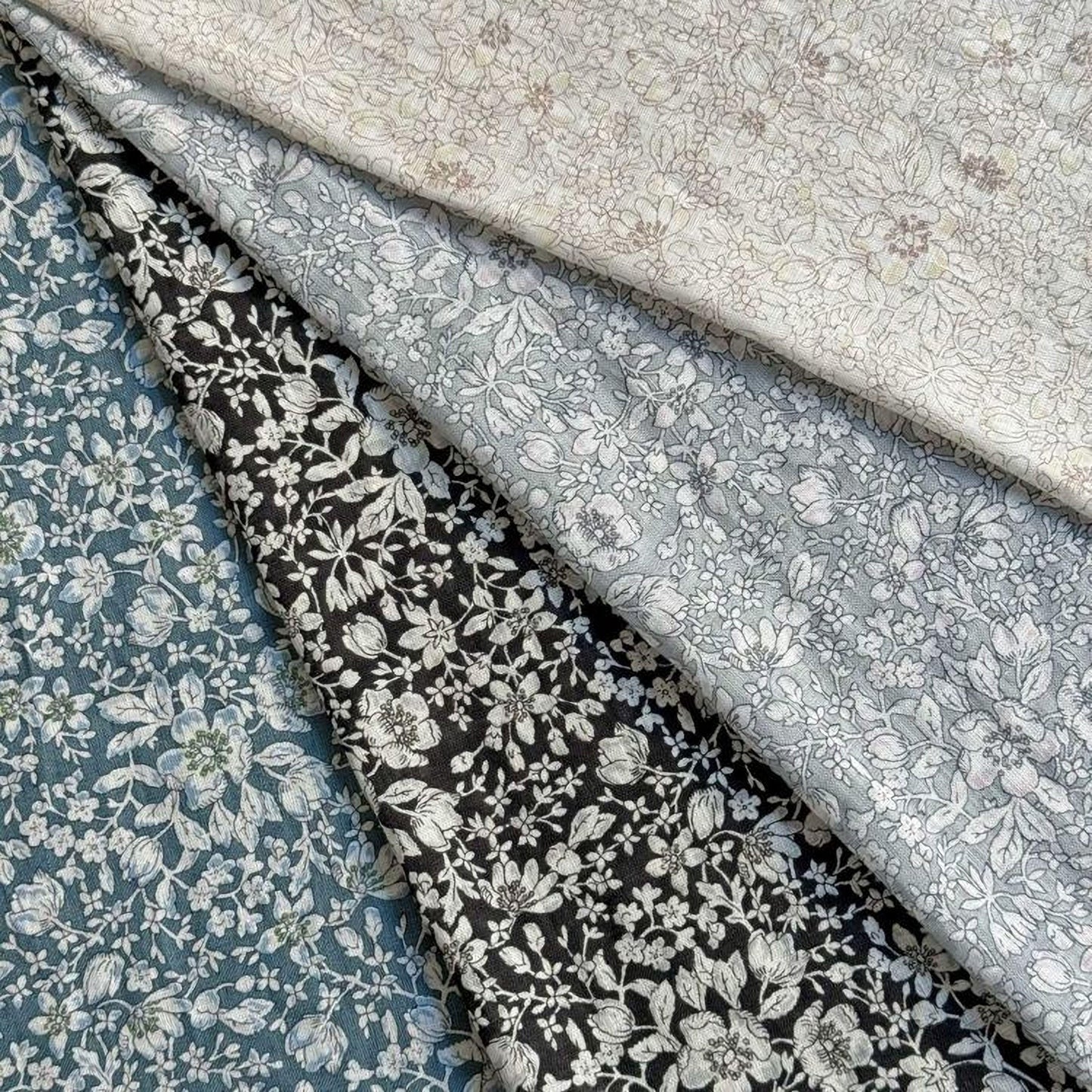 a collection of fabric swatches with various floral patterns, including white and gray floral designs.