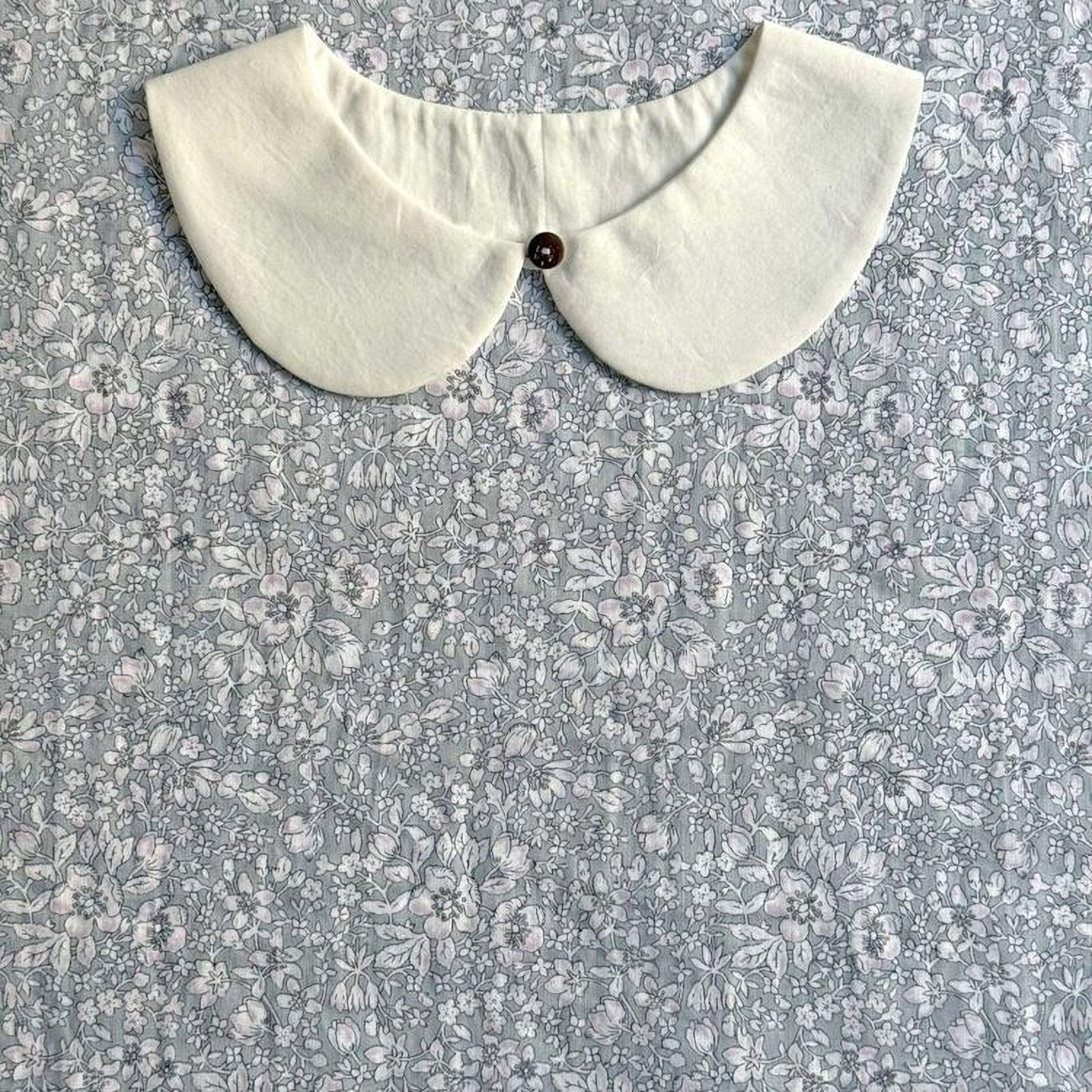 A white collar is displayed against a gray floral background.
