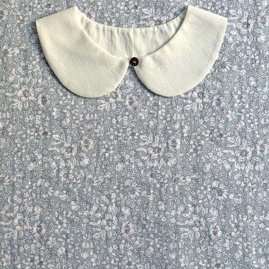 A white collar is displayed against a gray floral background.