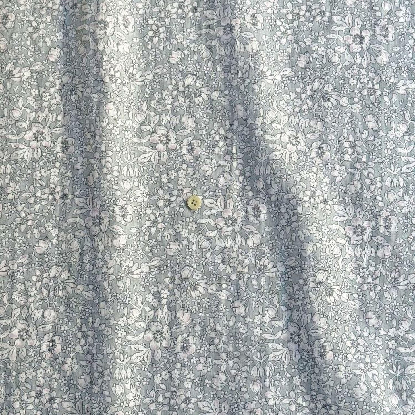 a close-up view of a fabric with a floral pattern, featuring a small button in the center.