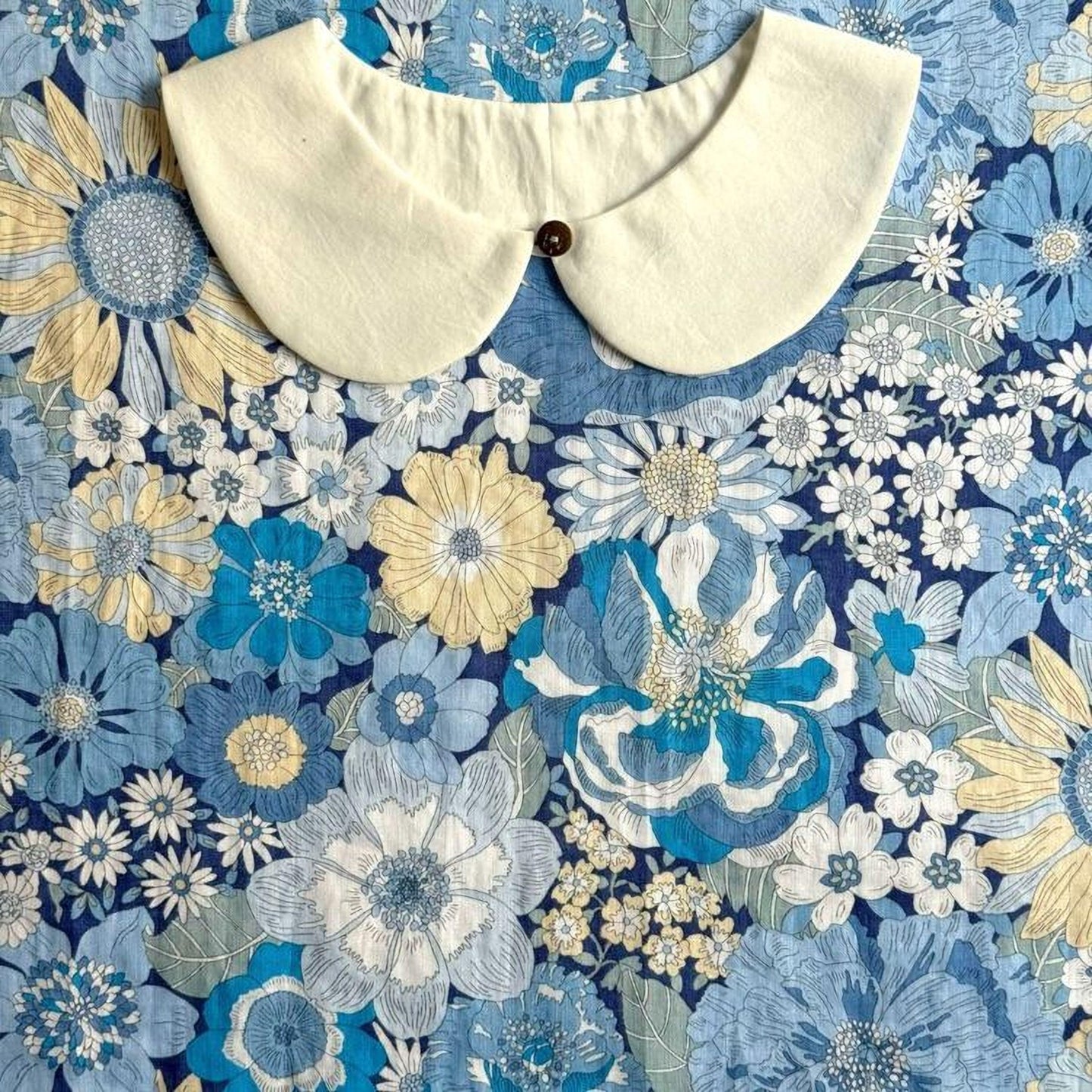 a white collar placed on a blue and white floral print background.