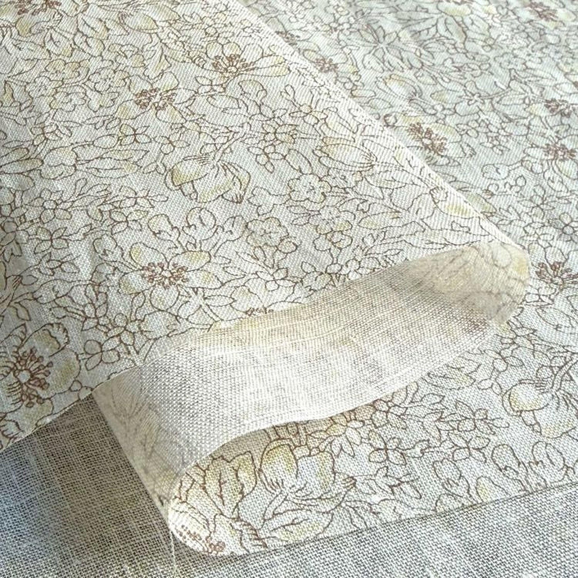 a close-up view of a fabric with a floral pattern, featuring a mix of brown and white colors.